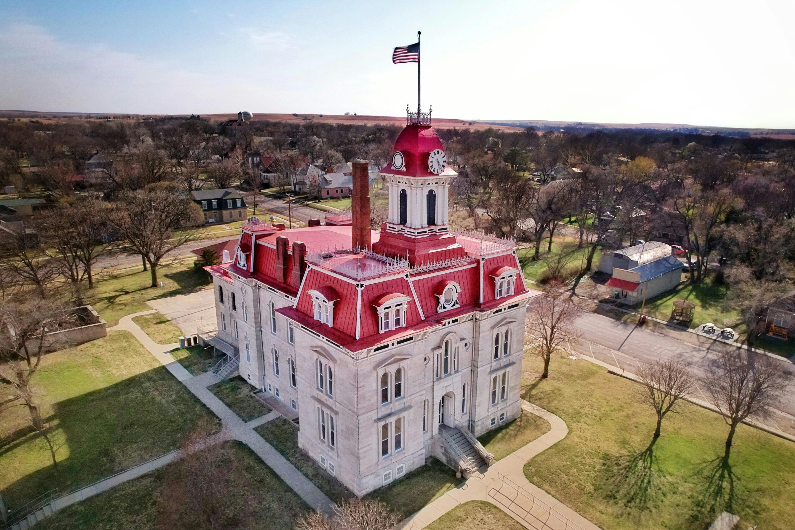 Historic courthouse building in Kansas with a red roof and American flag viewed from above.