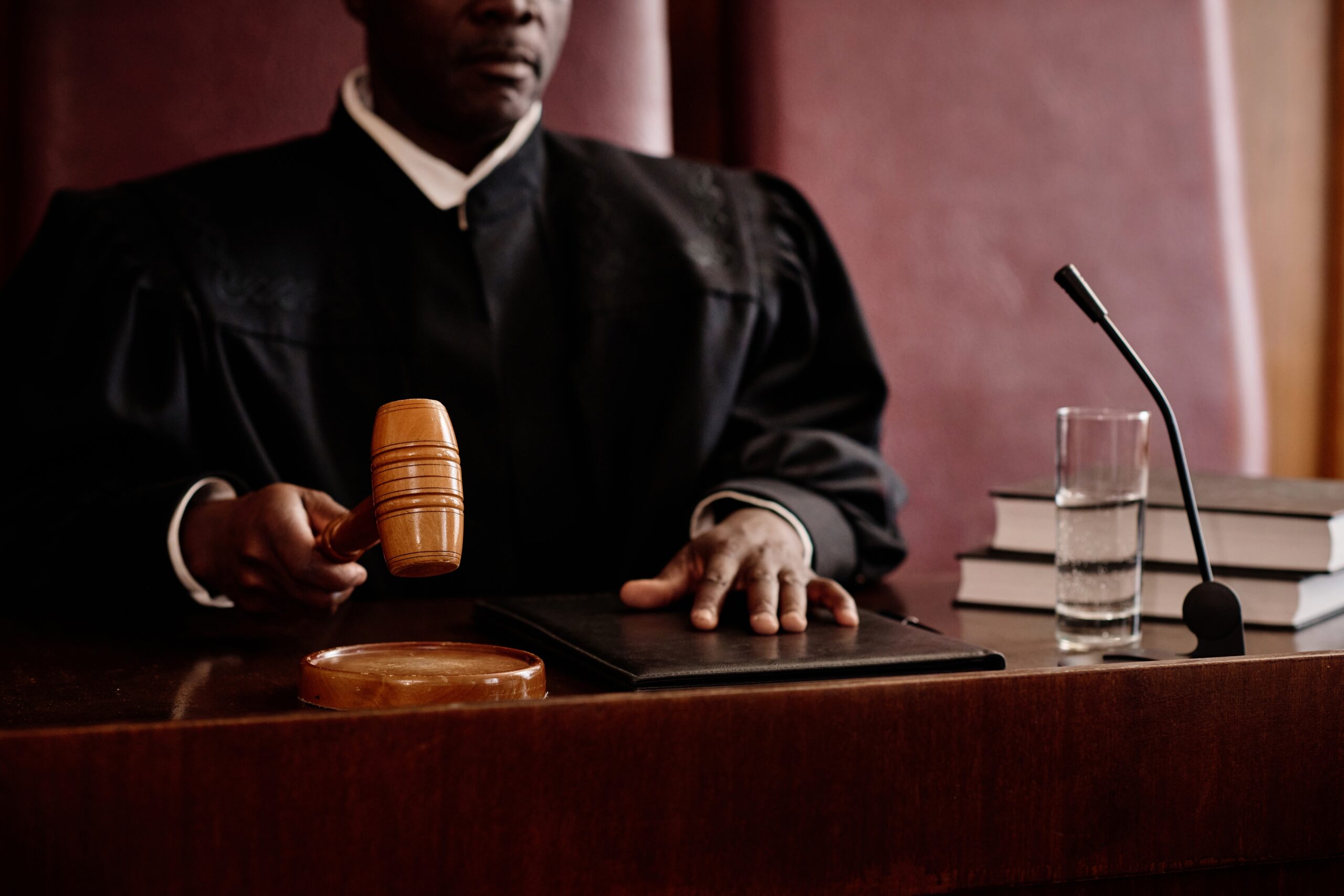 Judge holding gavel over bench during courtroom proceedings.