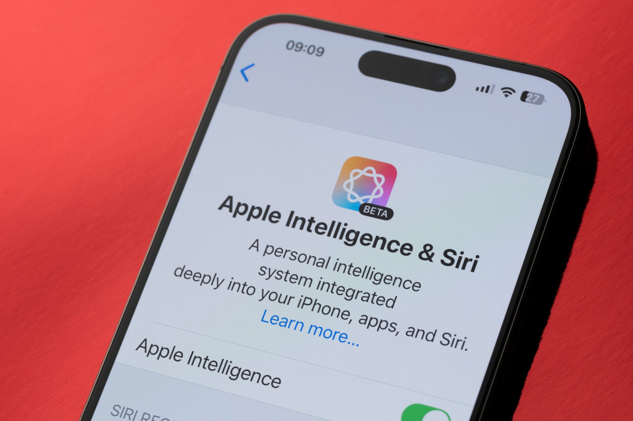 iPhone screen displaying Apple Intelligence and Siri beta settings on a red background.