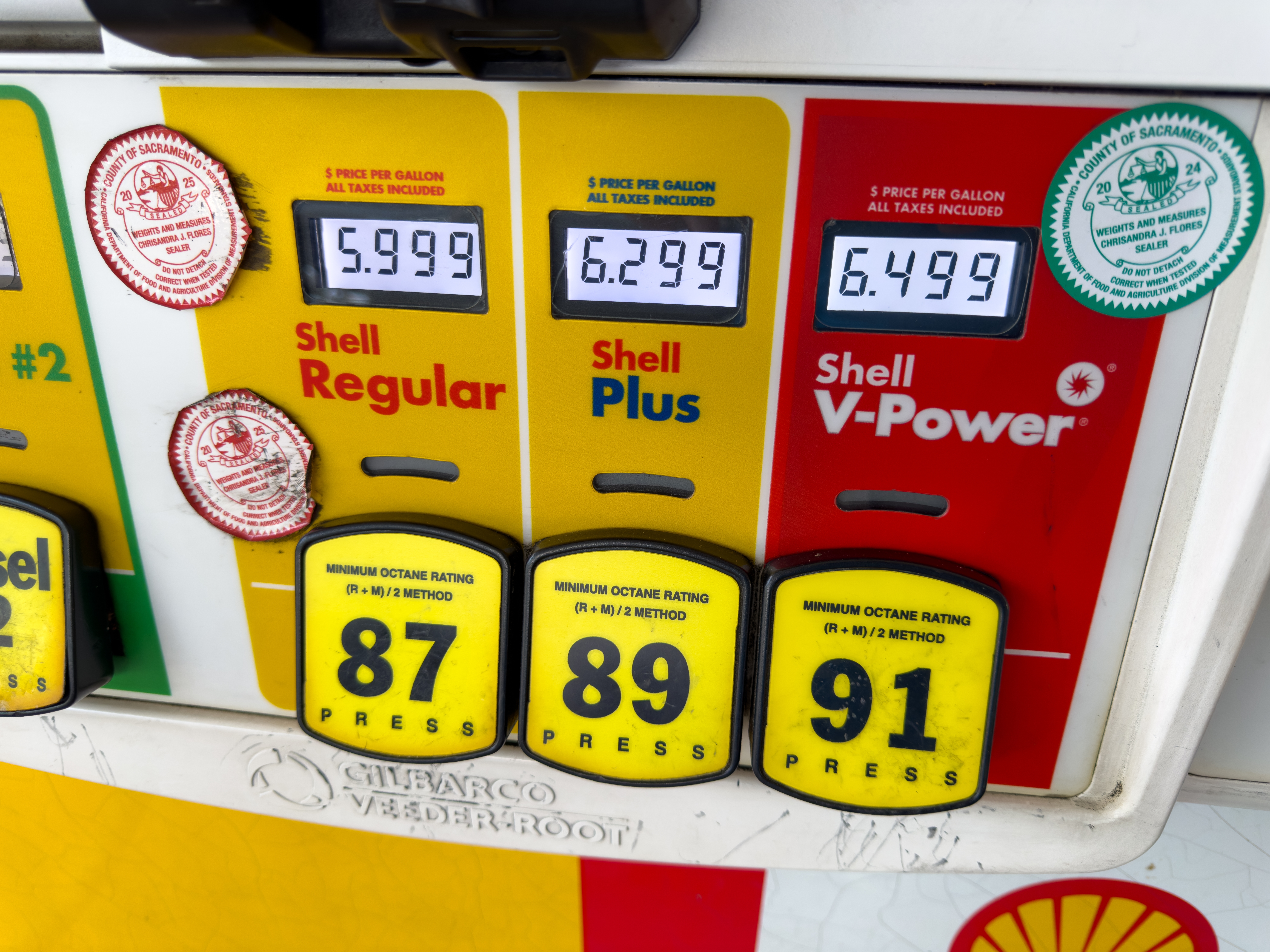 Shell gas pump displaying fuel prices for regular, plus, and premium gasoline.