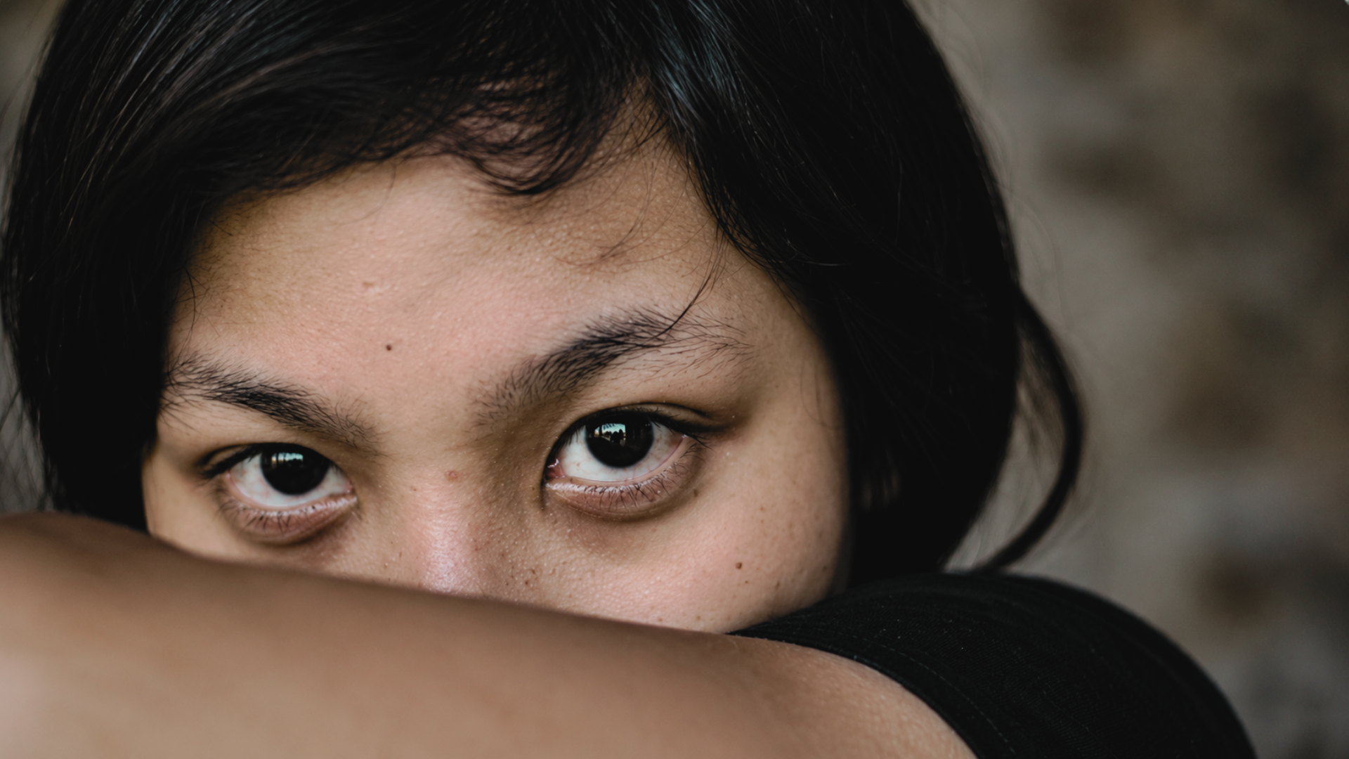 Close-up of a young person looking over their folded arms.