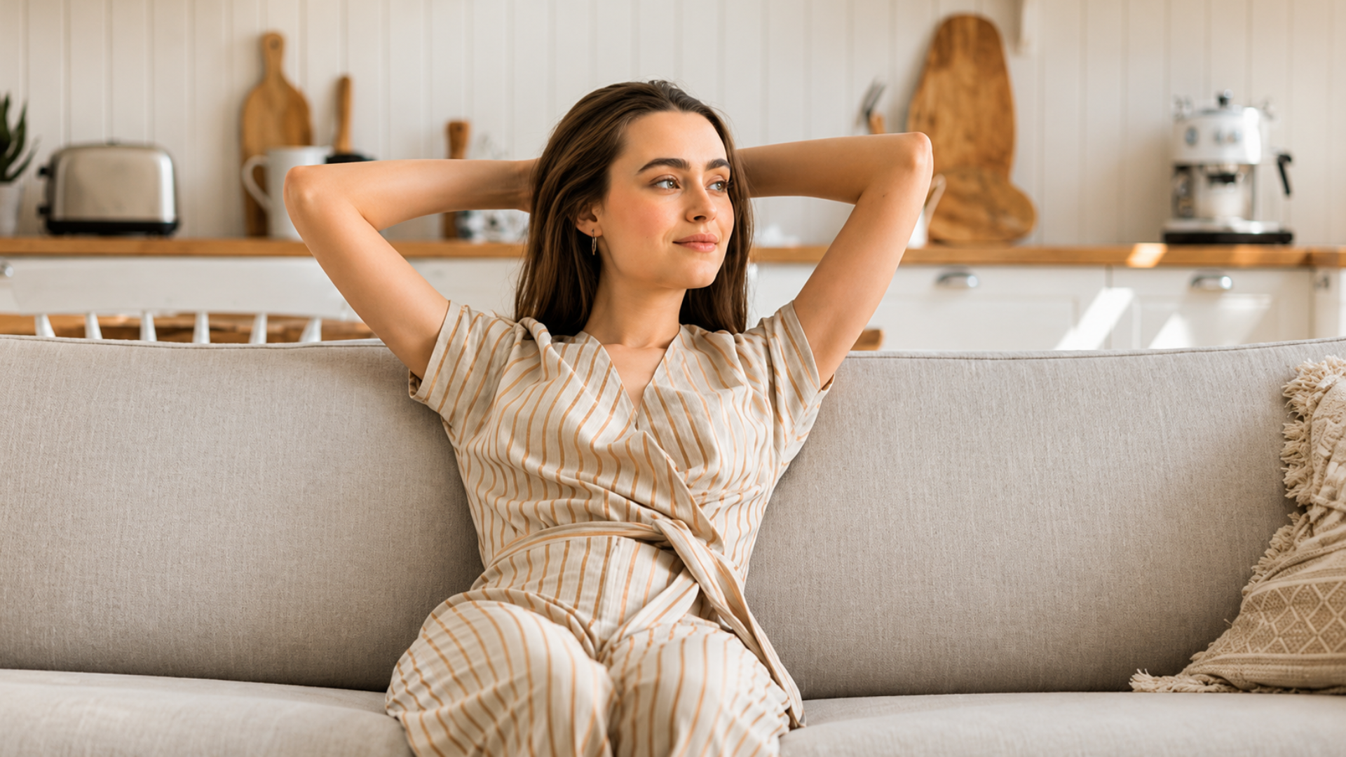 Woman relaxing on a couch with her hands behind her head.