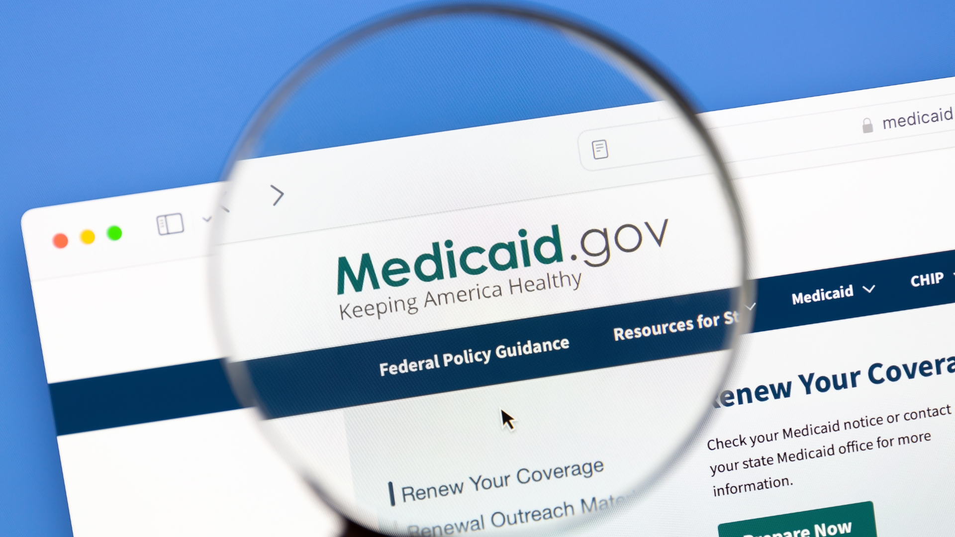 A magnifying glass focused on a computer screen displaying the homepage of the Medicaid.gov website.
