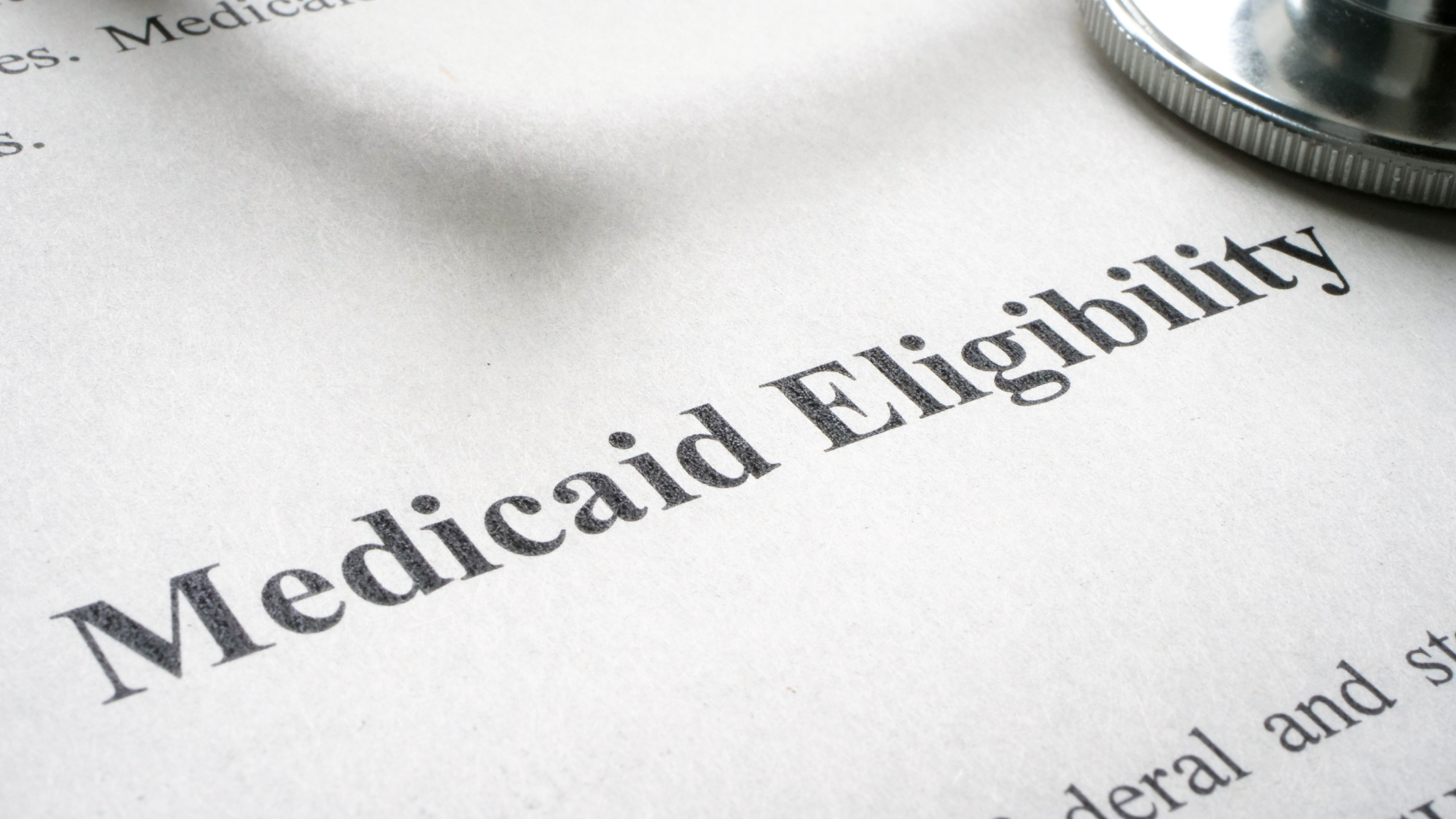 A close-up of a printed document with the large heading "Medicaid Eligibility" and a portion of a stethoscope resting on the top right corner.