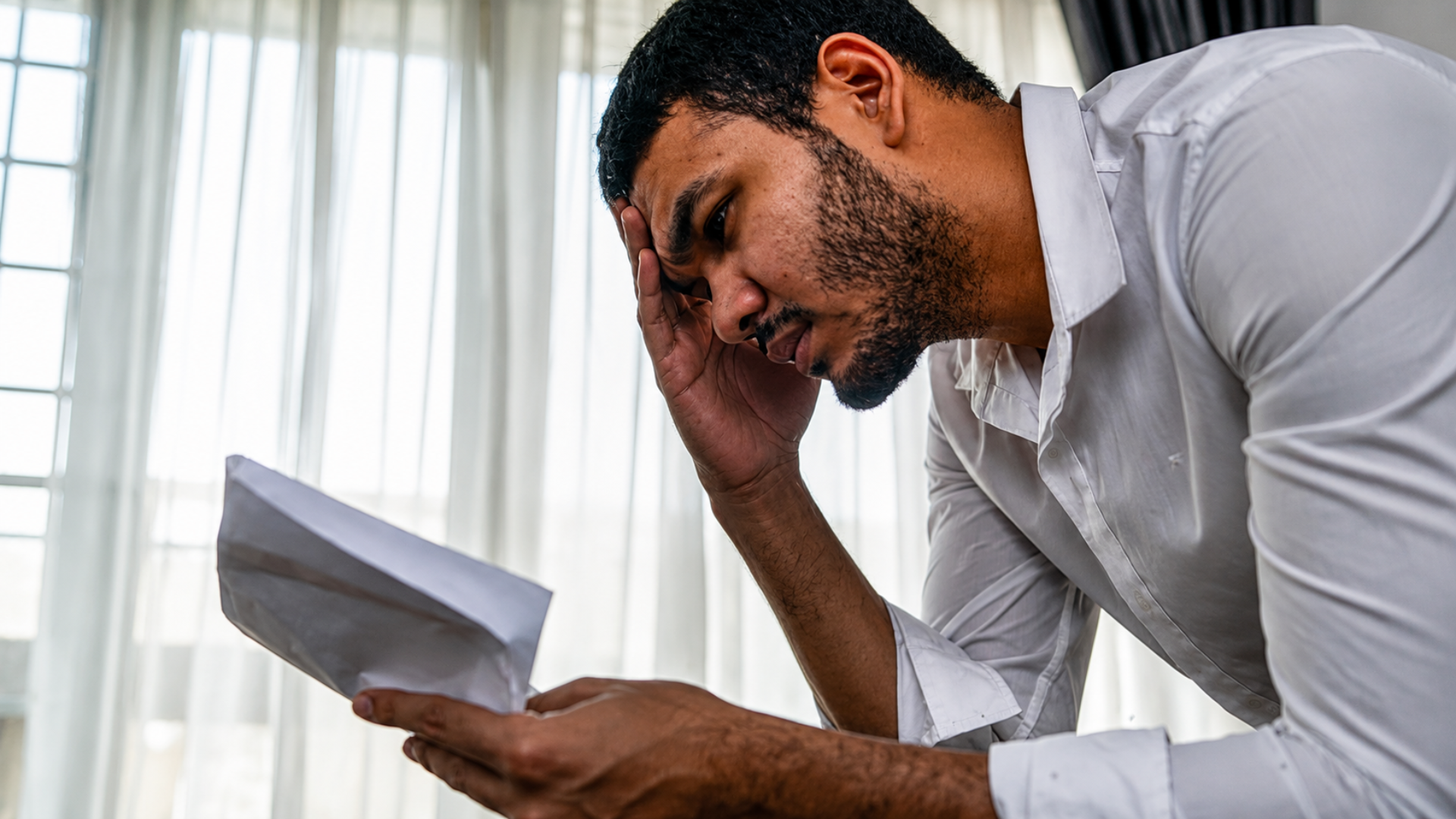Man holding his head while reading documents indoors.