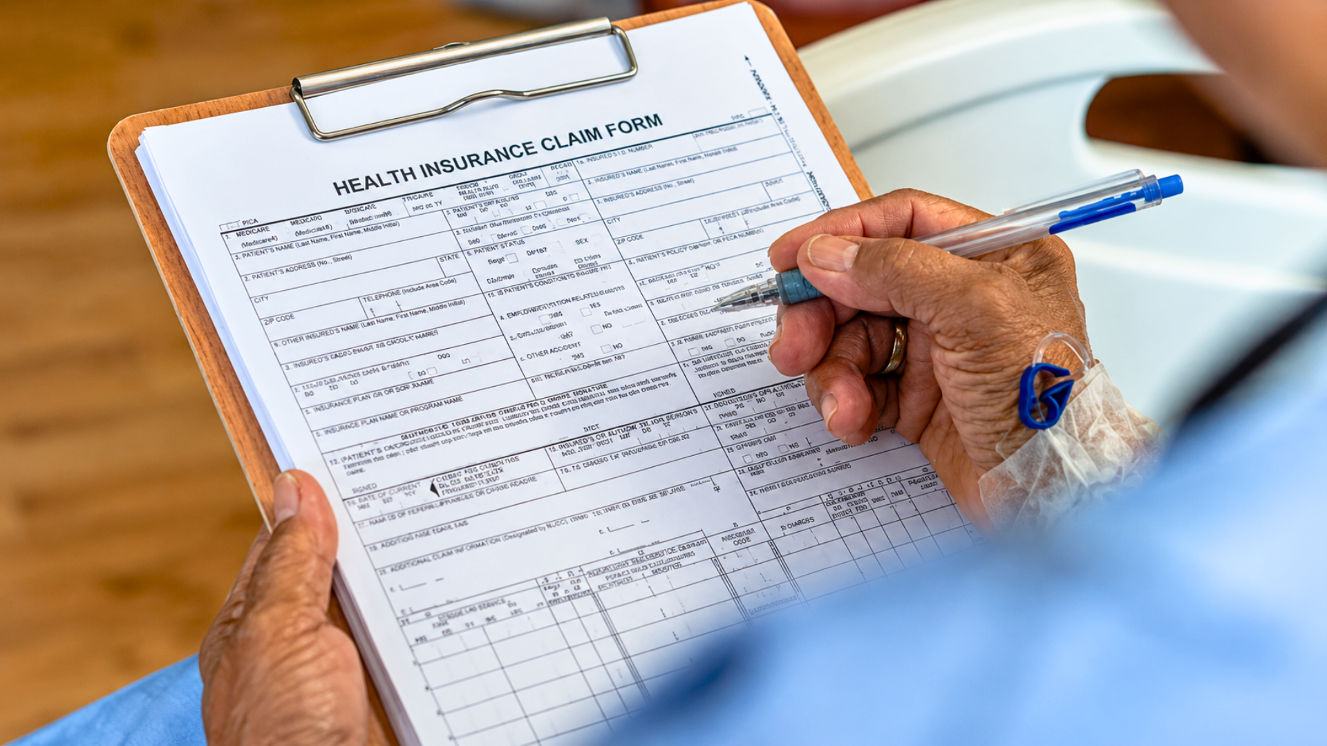 Person filling out a health insurance claim form on a clipboard.