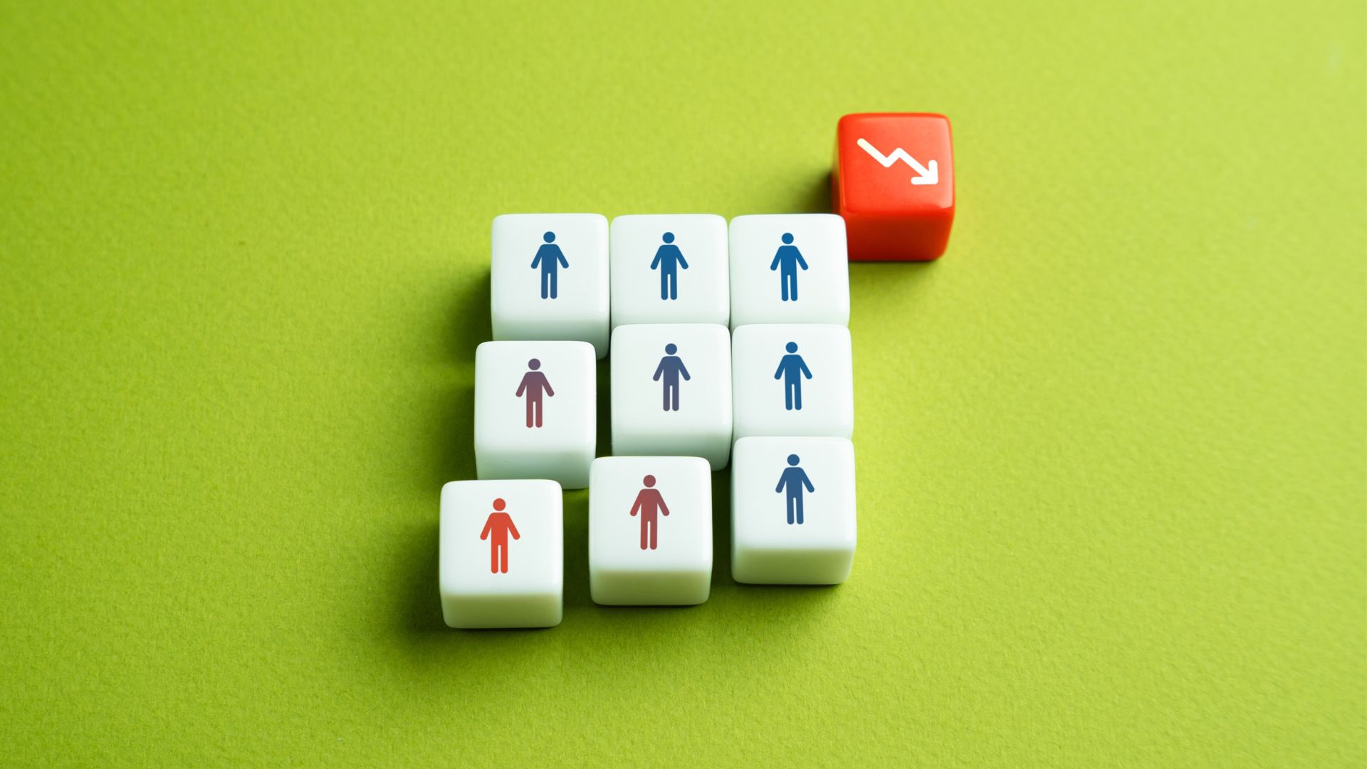 Toy cubes with human figures and a downward arrow symbolizing population decline.