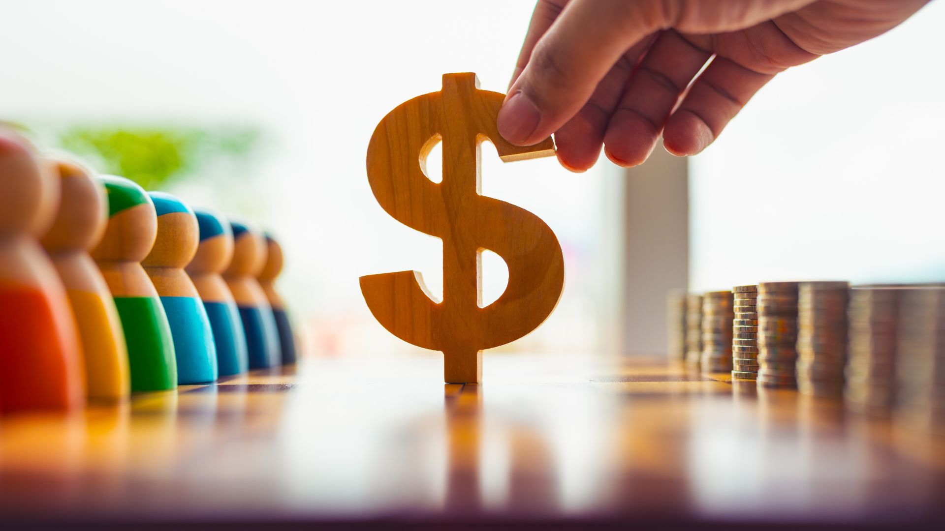 Close take of the hand of a person holding the money symbol in the middle of a table.