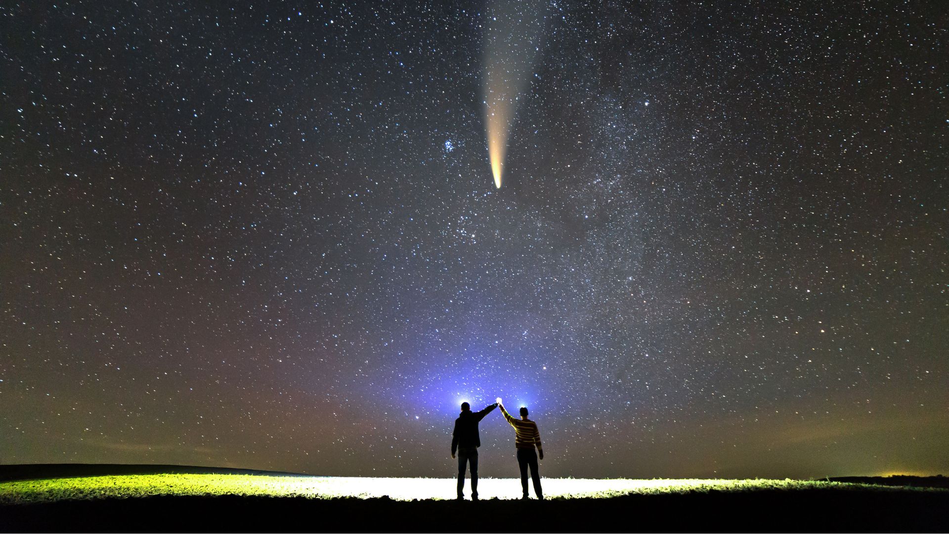 Two people beneath a night sky, watching a bright star-like signal from space.