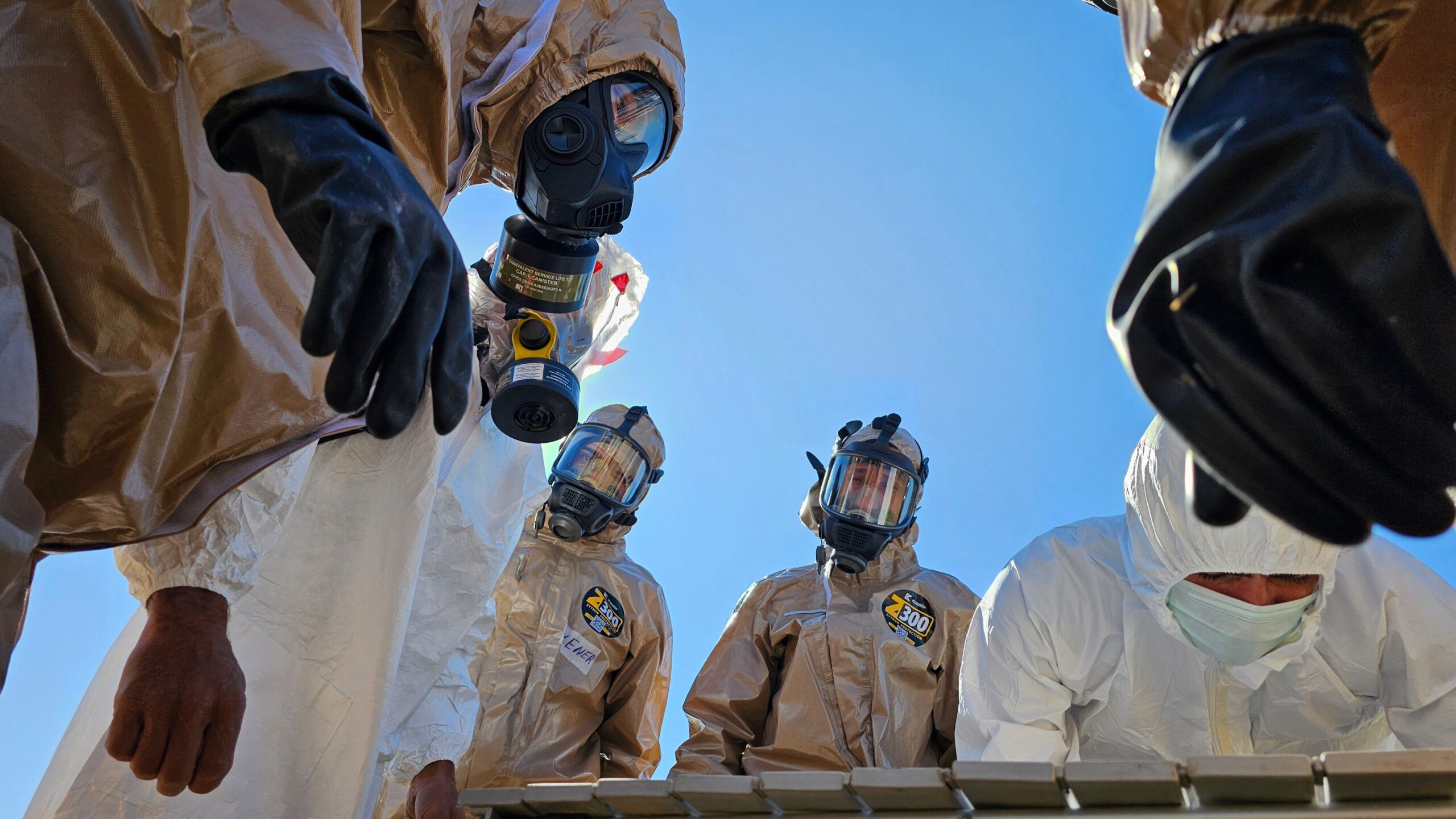 Emergency response personnel wearing full protective gear participate in a disease containment exercise.
