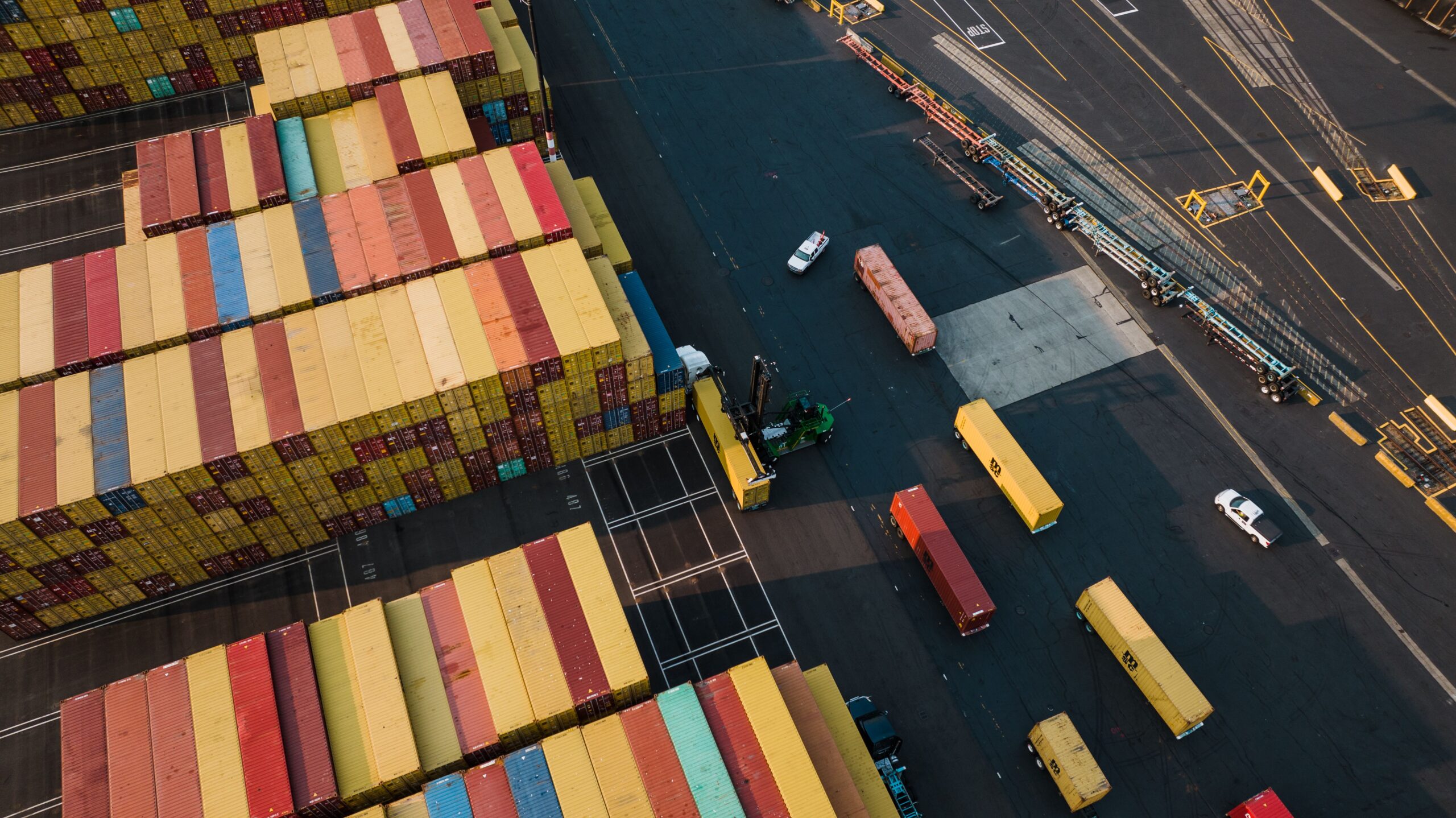 Aerial view of shipping containers stacked at a busy cargo port.