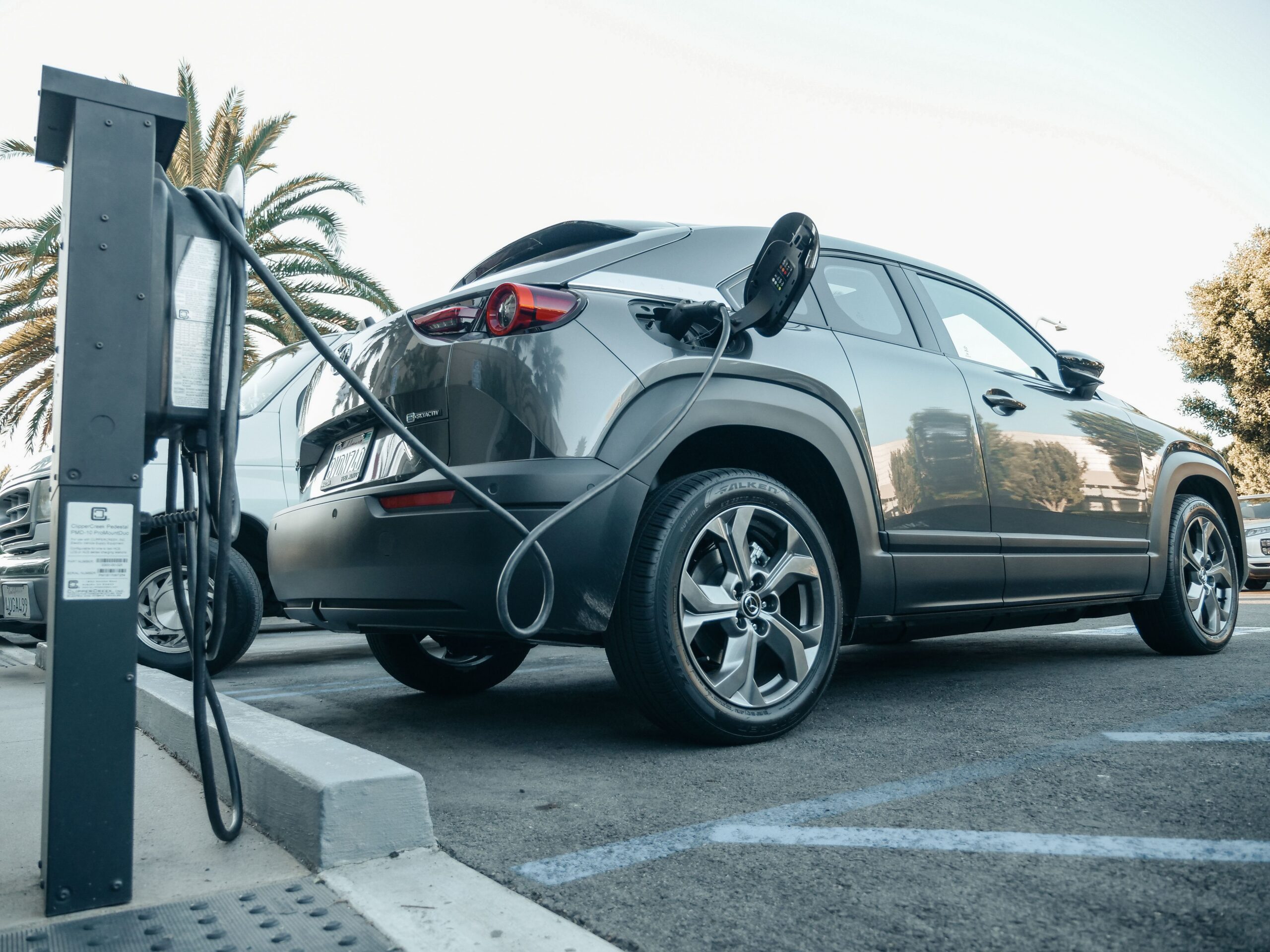 Electric SUV connected to a charging station in a public parking lot.
