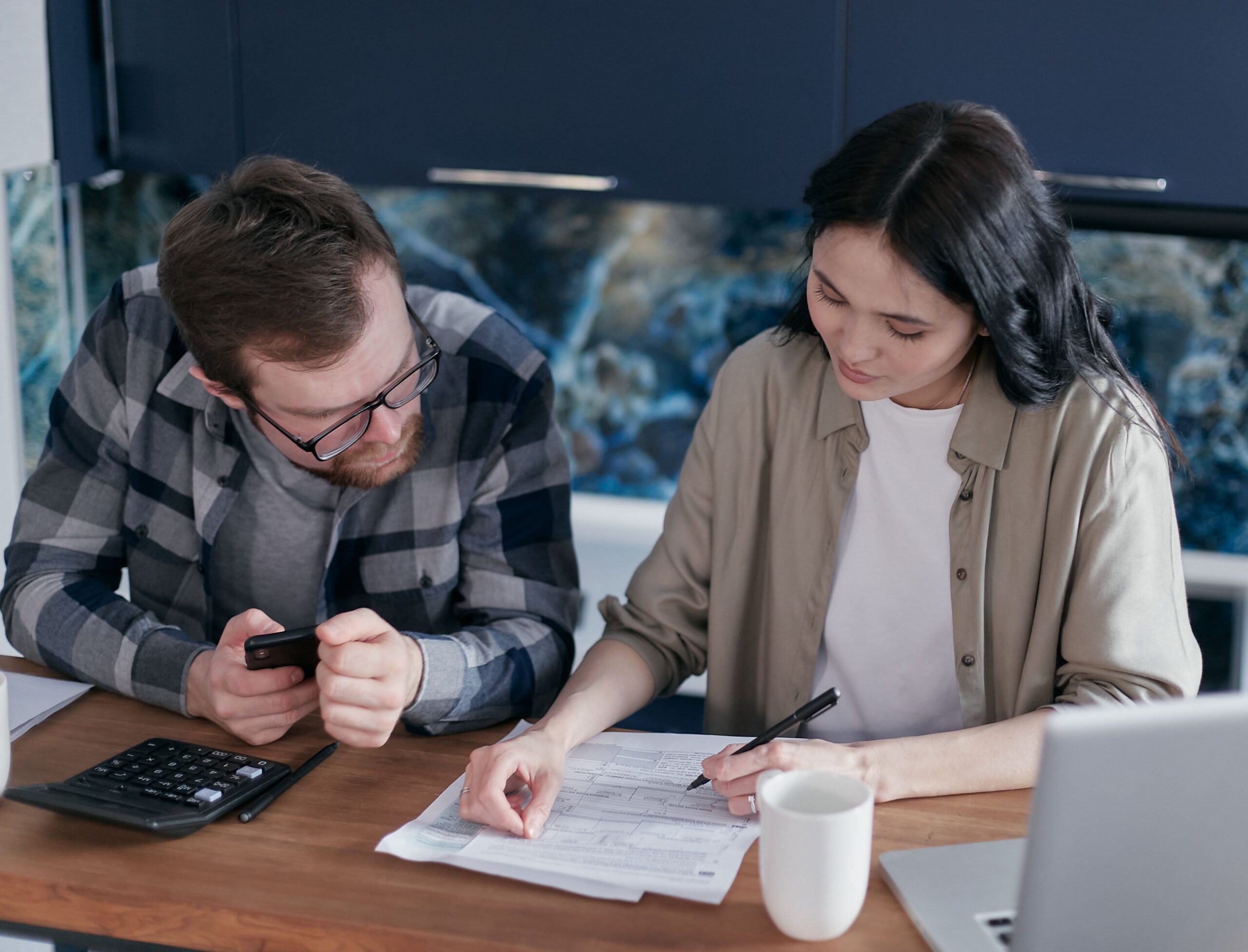 Couple reviewing electricity bills and financial documents at a kitchen table.