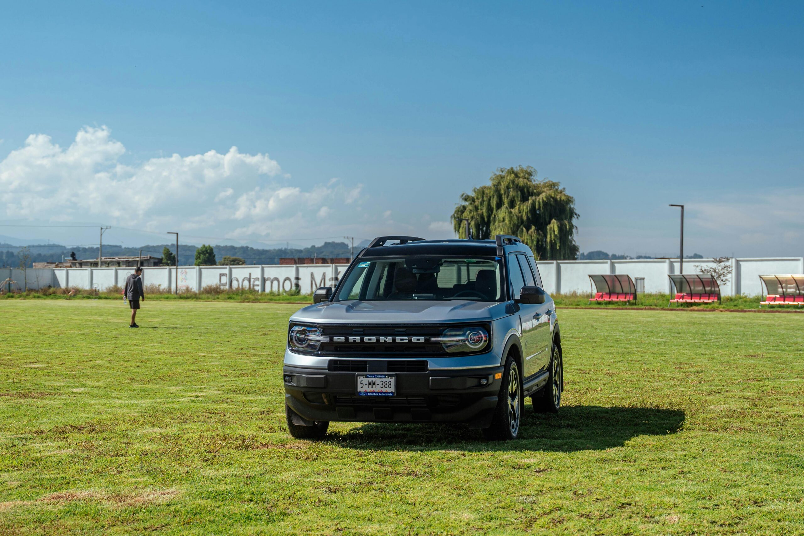 Ford Bronco Sport SUV parked on a grassy field under a clear blue sky.