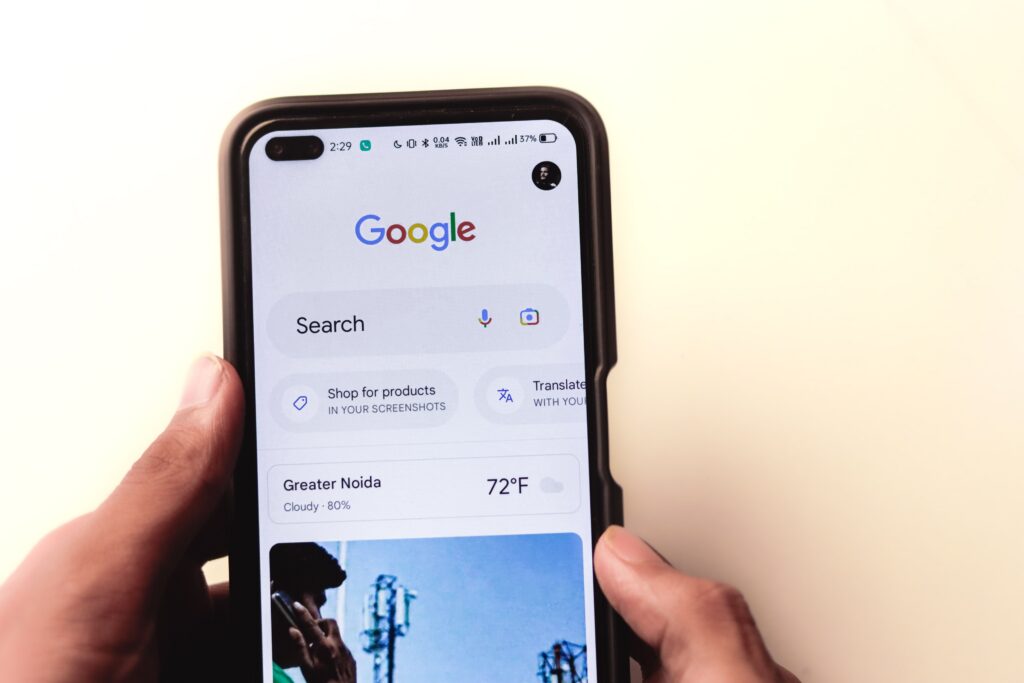 Person holding a smartphone displaying the Google search app home screen.