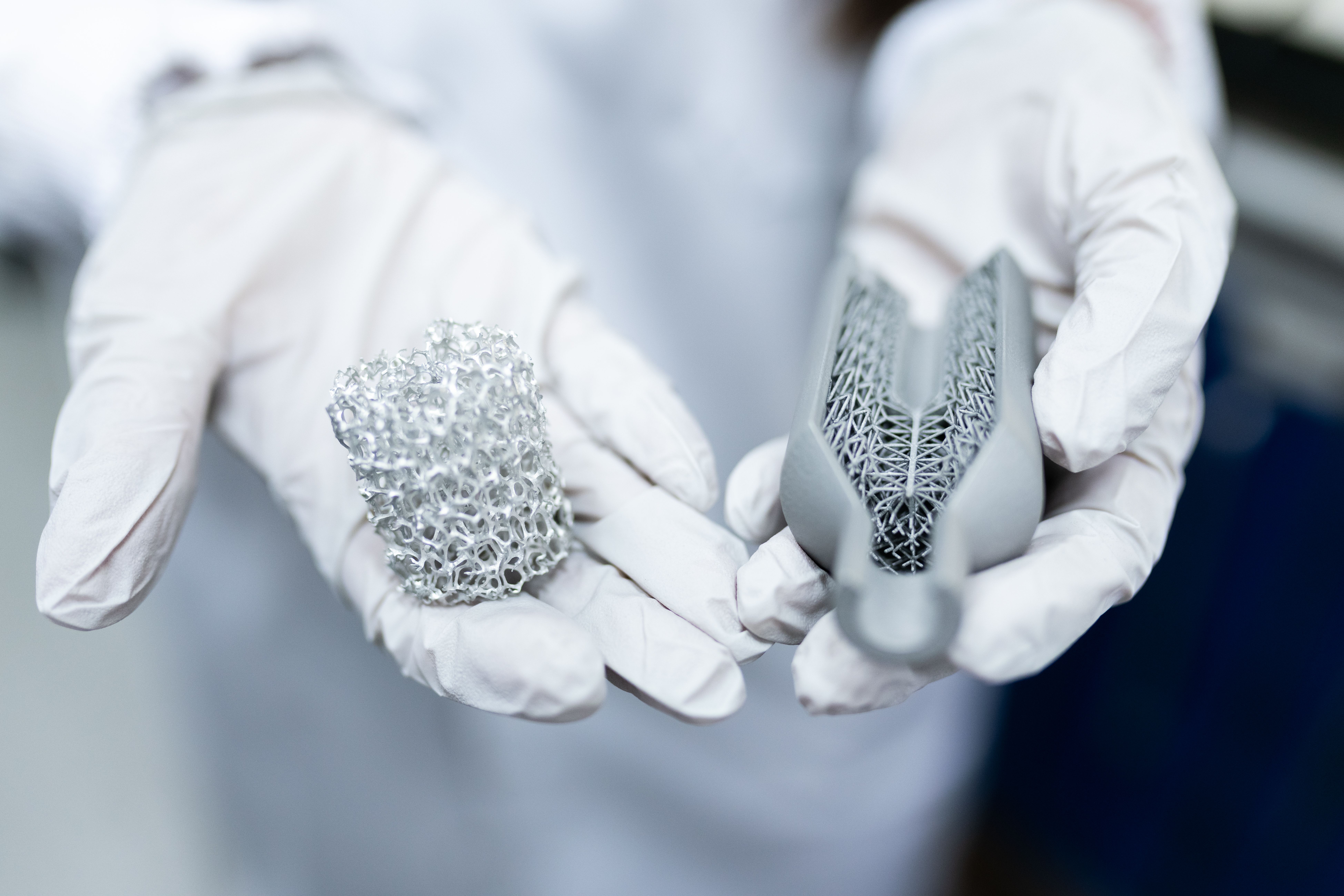Gloved hands display complex parts made with 3D-printing technology.