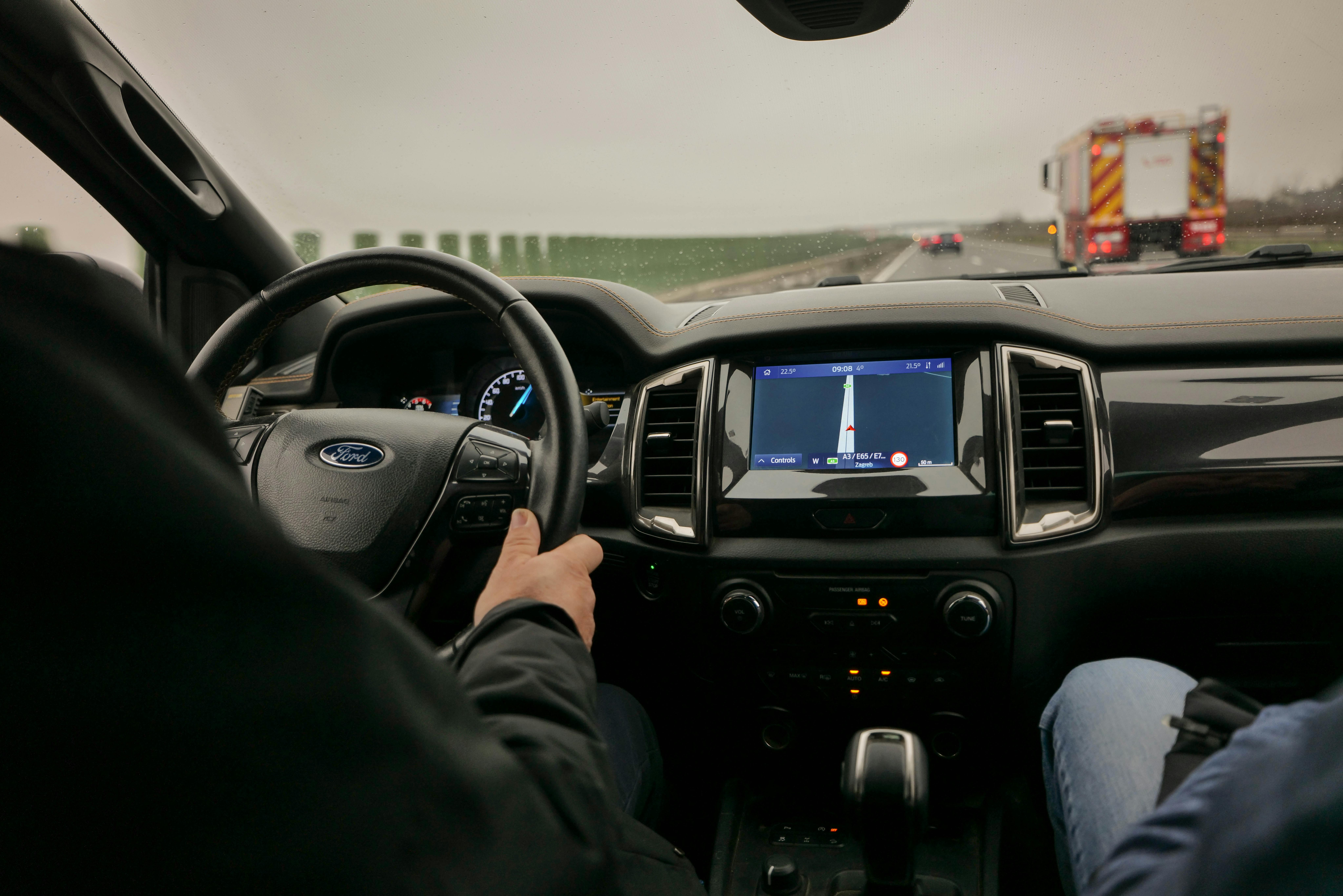 Driver’s view inside a Ford vehicle with navigation screen displayed on a highway.