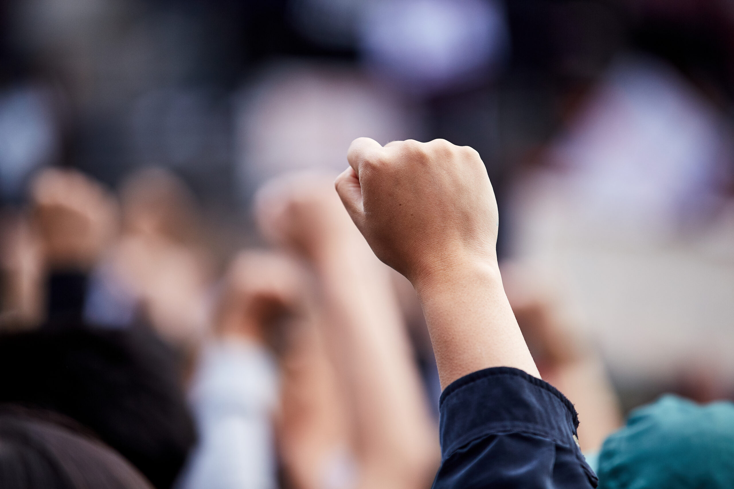 Raised fist in a crowd, symbolizing activism, worker rights advocacy, and public calls for accountability.