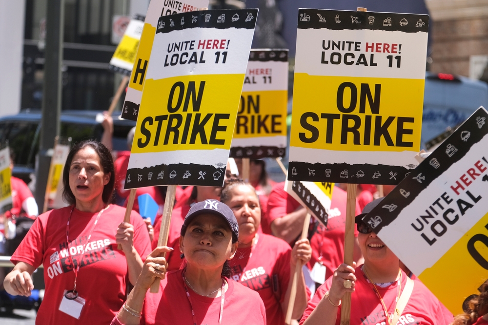 Striking hotel workers holding signs rally outside