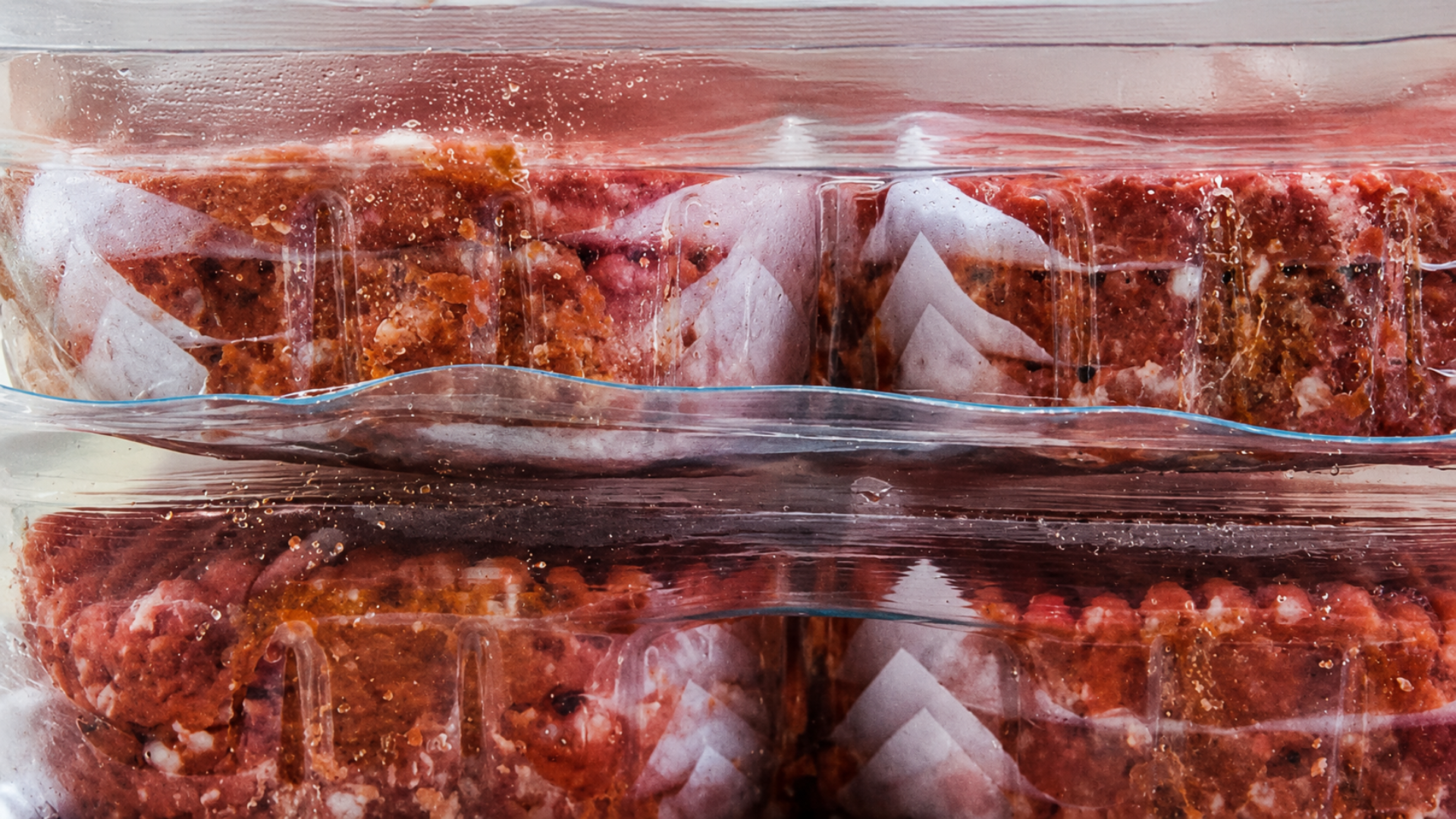 Vacuum-sealed packages of frozen ground beef stacked in a freezer for storage.