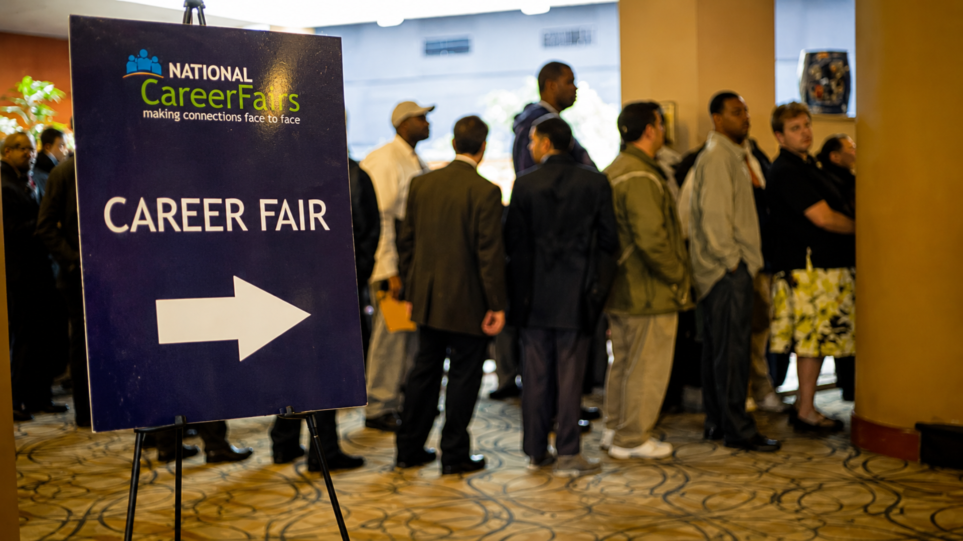 Career fair sign directing job seekers toward a line of attendees.