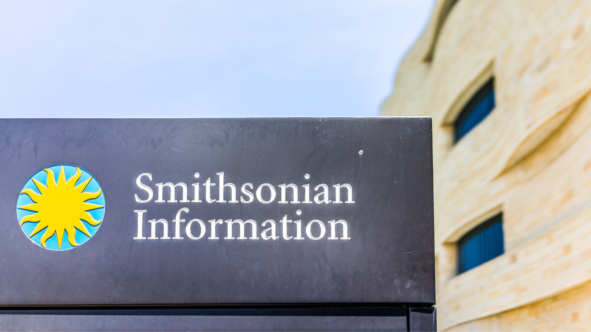 A black sign displaying the Smithsonian sunburst logo and the words