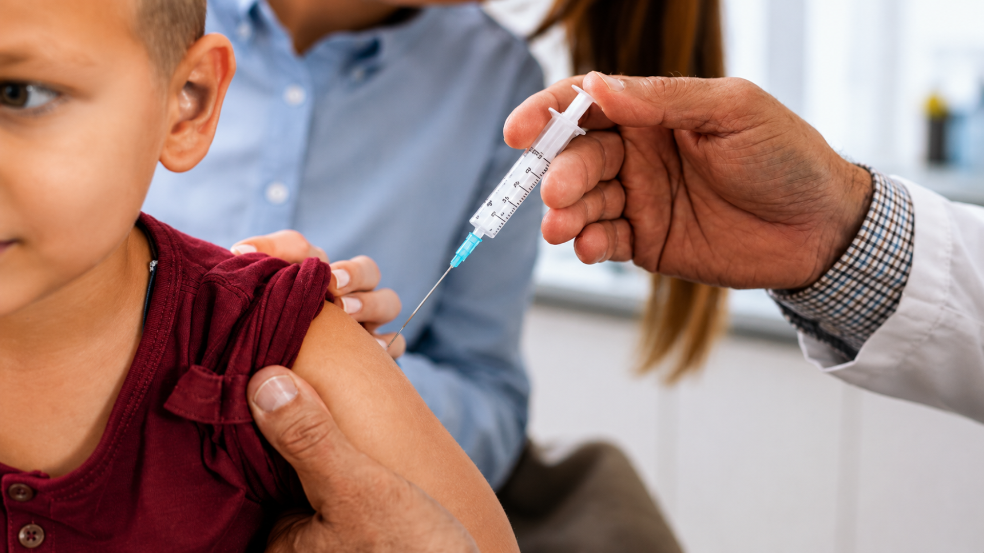 A healthcare worker holding a syringe to administer a vaccine into a young boy's arm.