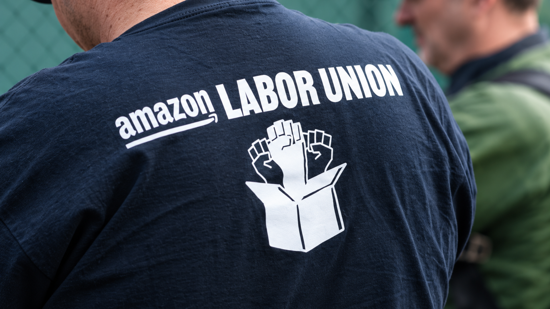 A person wearing a dark shirt printed with the Amazon Labor Union logo.