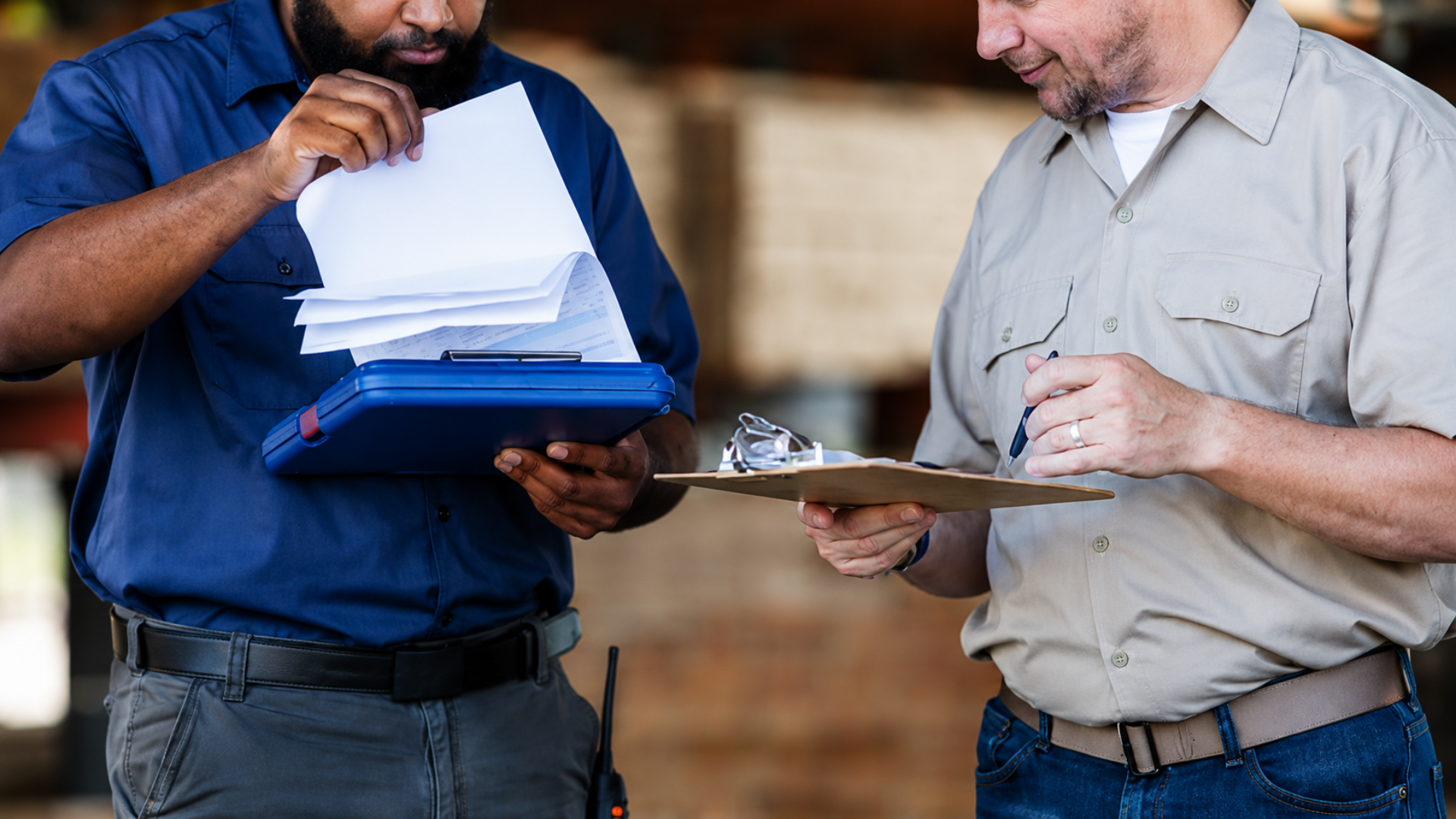 Two workers reviewing paperwork and inventory records at a lumber yard.