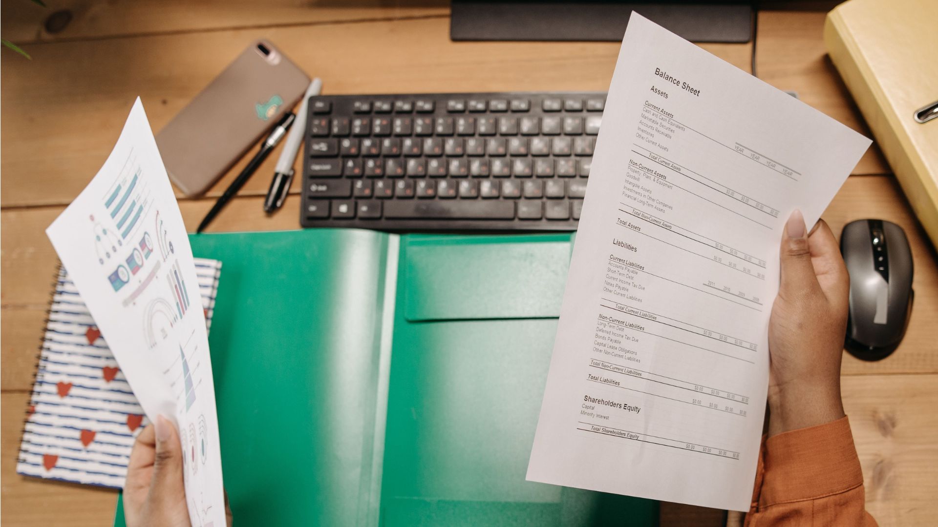 Hands holding a printed balance sheet with assets and liabilities.