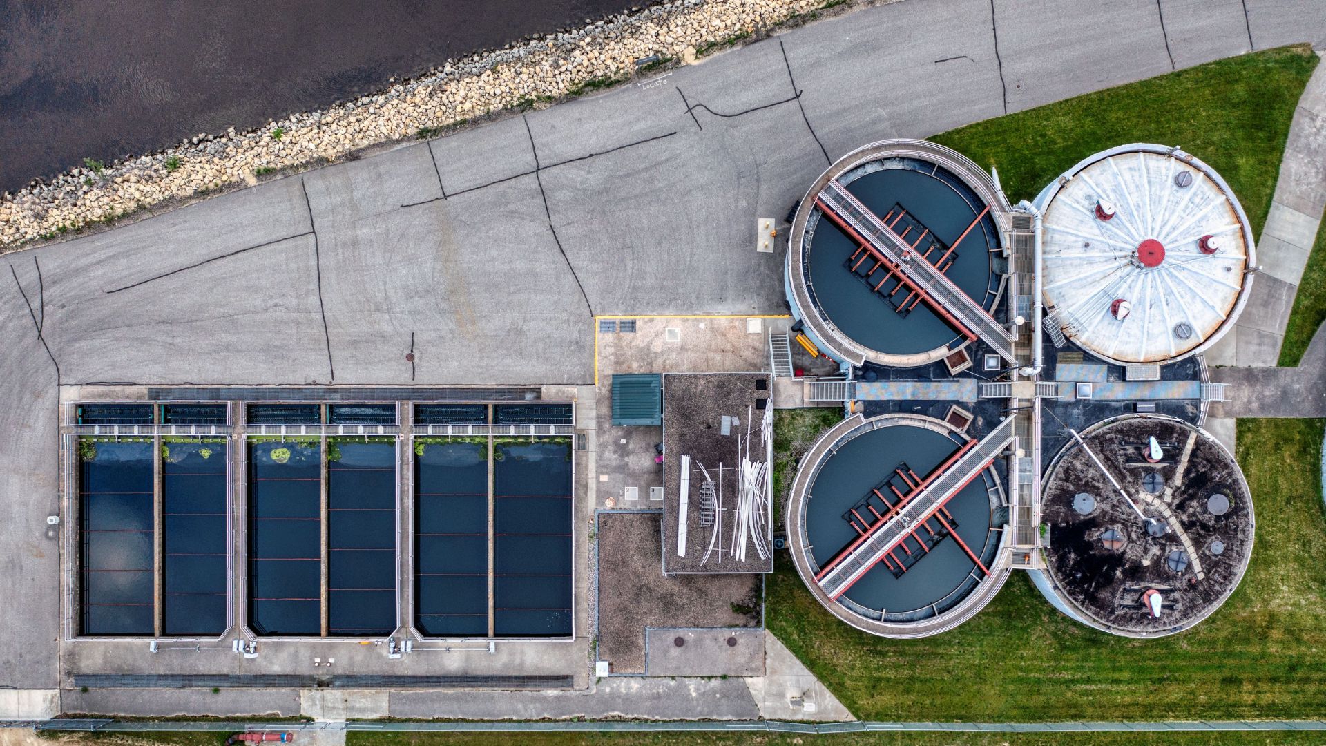 Aerial view of rectangular filtration beds and circular tanks at a water treatment plant.
