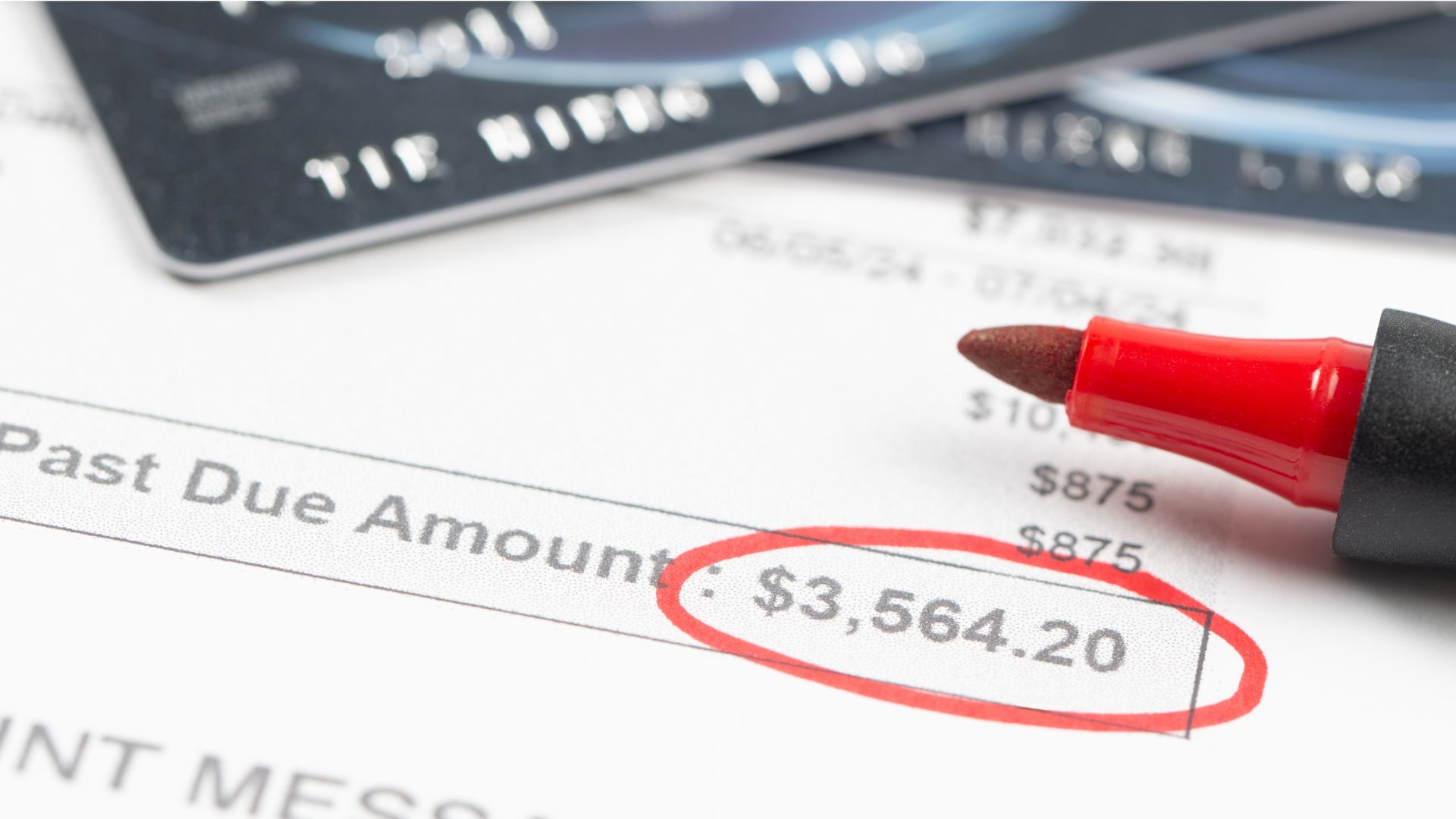 A past due balance circled in red marker with credit cards scattered on the paper.