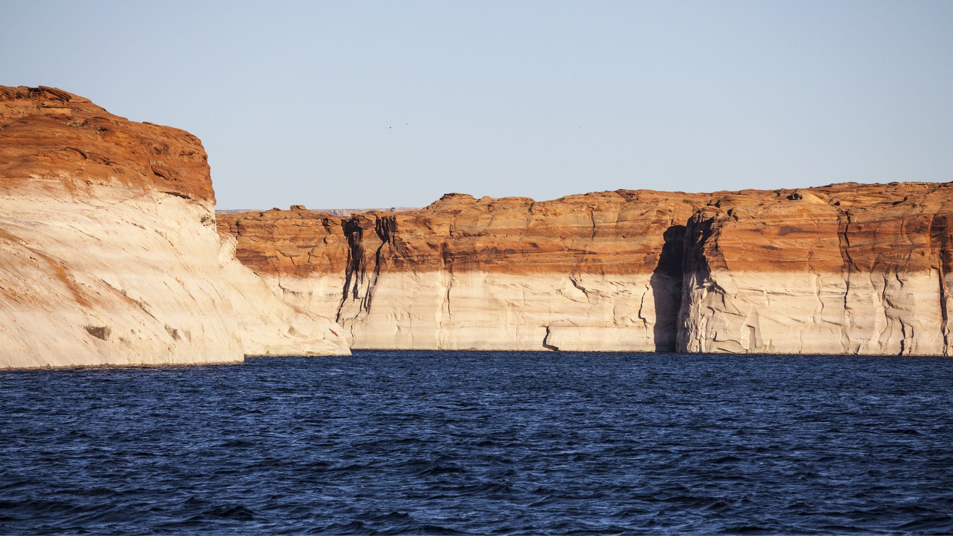 Water-level view of Lake Powell's canyon walls, showing the pale "bathtub ring" of exposed rock left by falling water levels.
