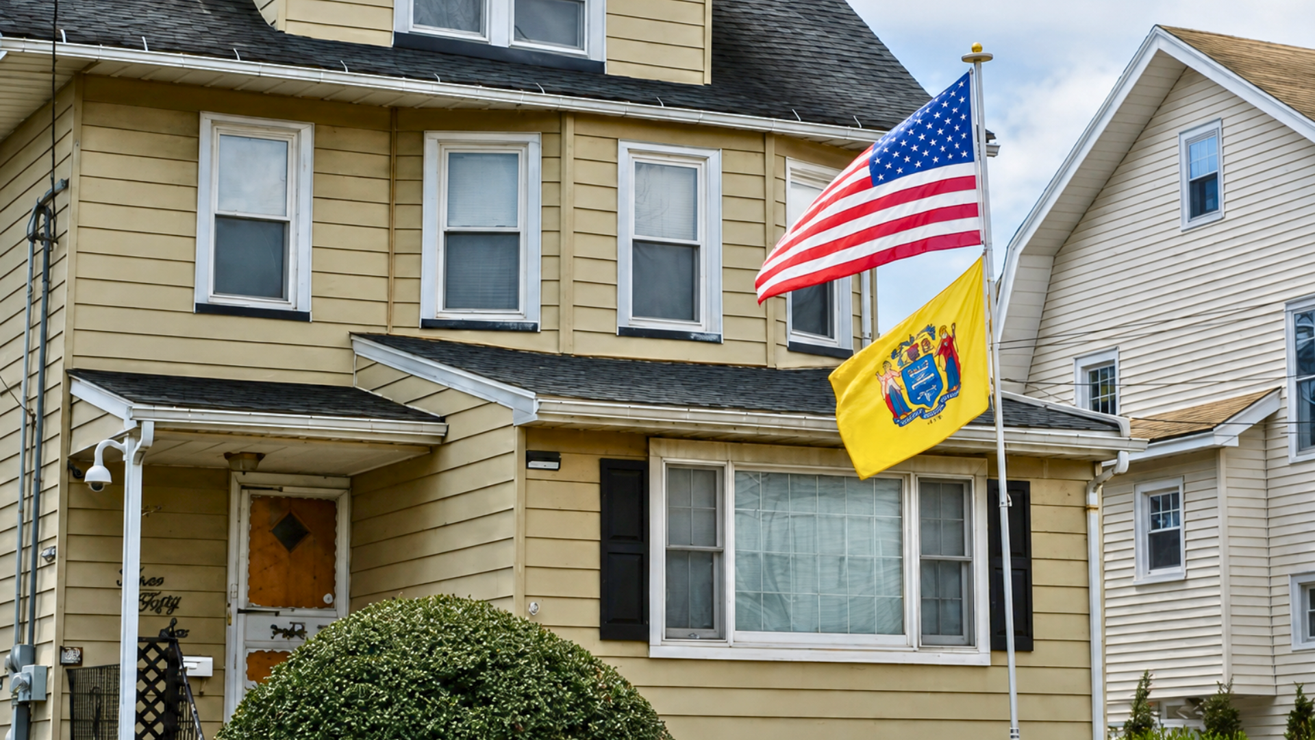 American and New Jersey flags flying outside a residential home.