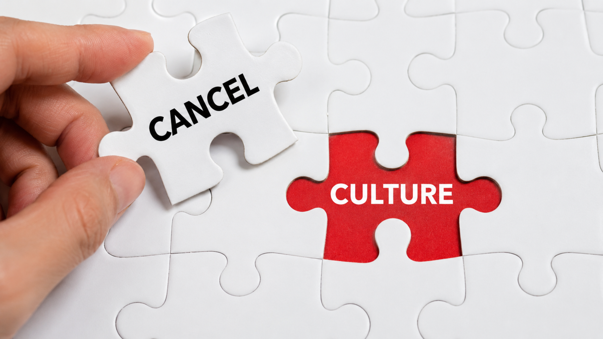 A hand placing a puzzle piece marked "CANCEL" into a slot labeled "CULTURE" on a white jigsaw puzzle.