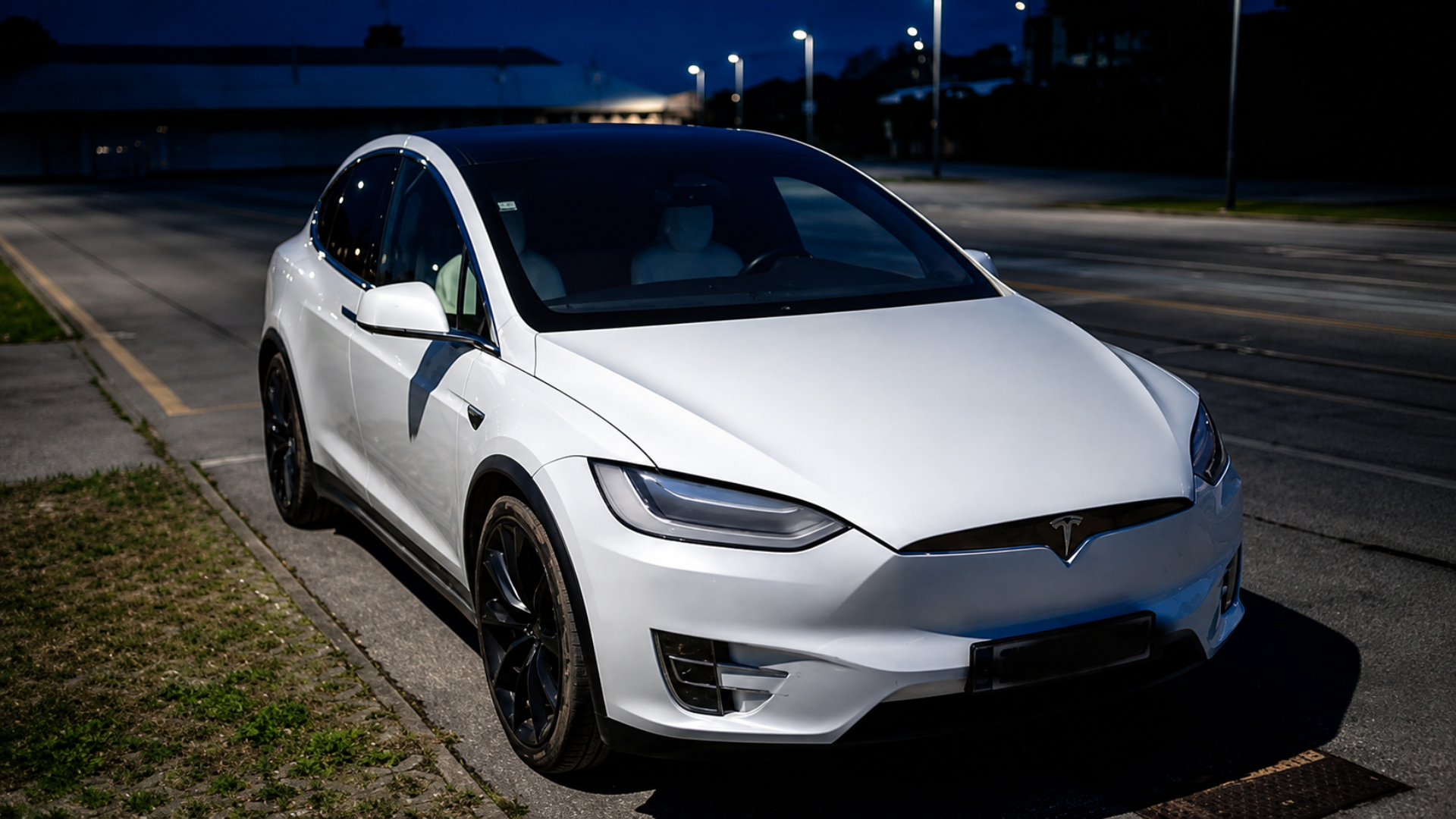 A white Tesla Model X parked outdoors at dusk.