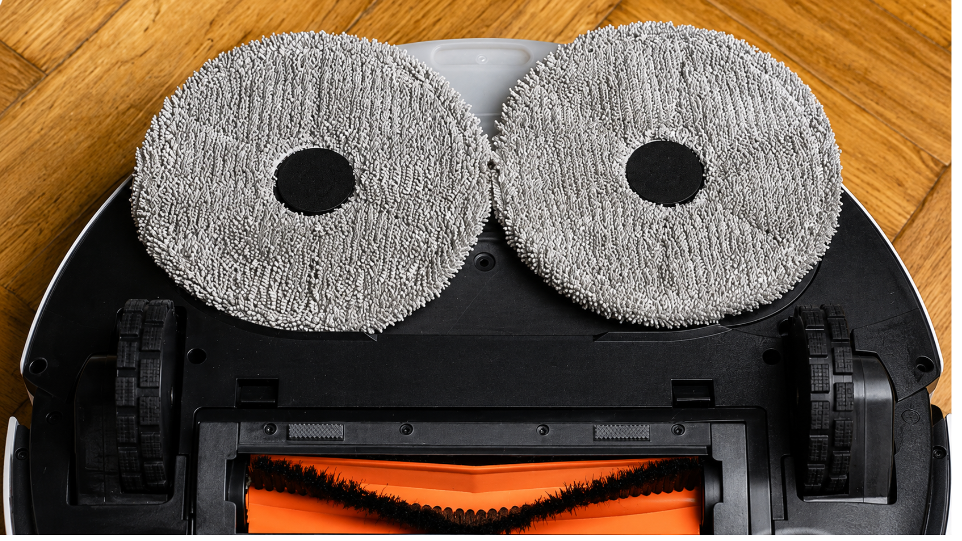 Underside of a robot vacuum showing dual rotating mop pads and cleaning brush.