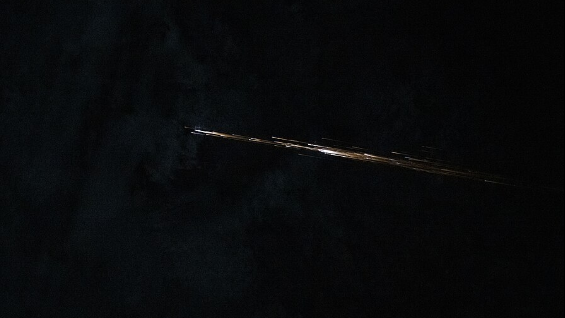 Bright streak crosses the dark lunar sky, illustrating a meteor impact on the Moon.