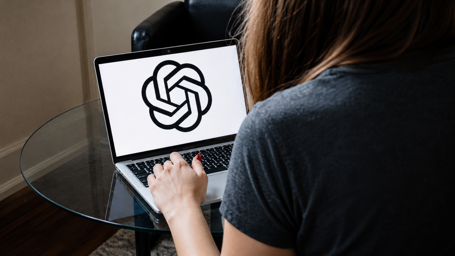A woman using a laptop displaying the OpenAI logo on the screen.