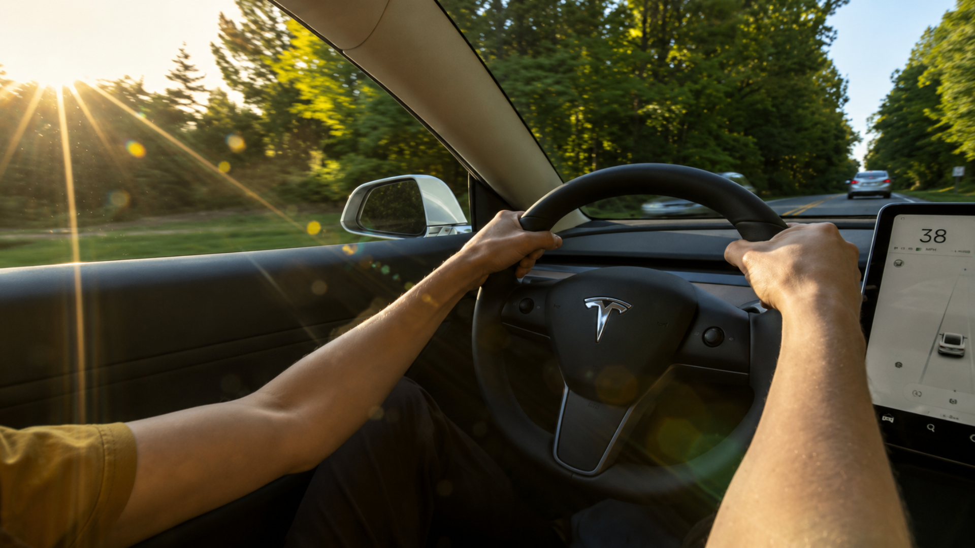 Driver's point-of-view inside a Tesla steering along a sunny road at sunset.