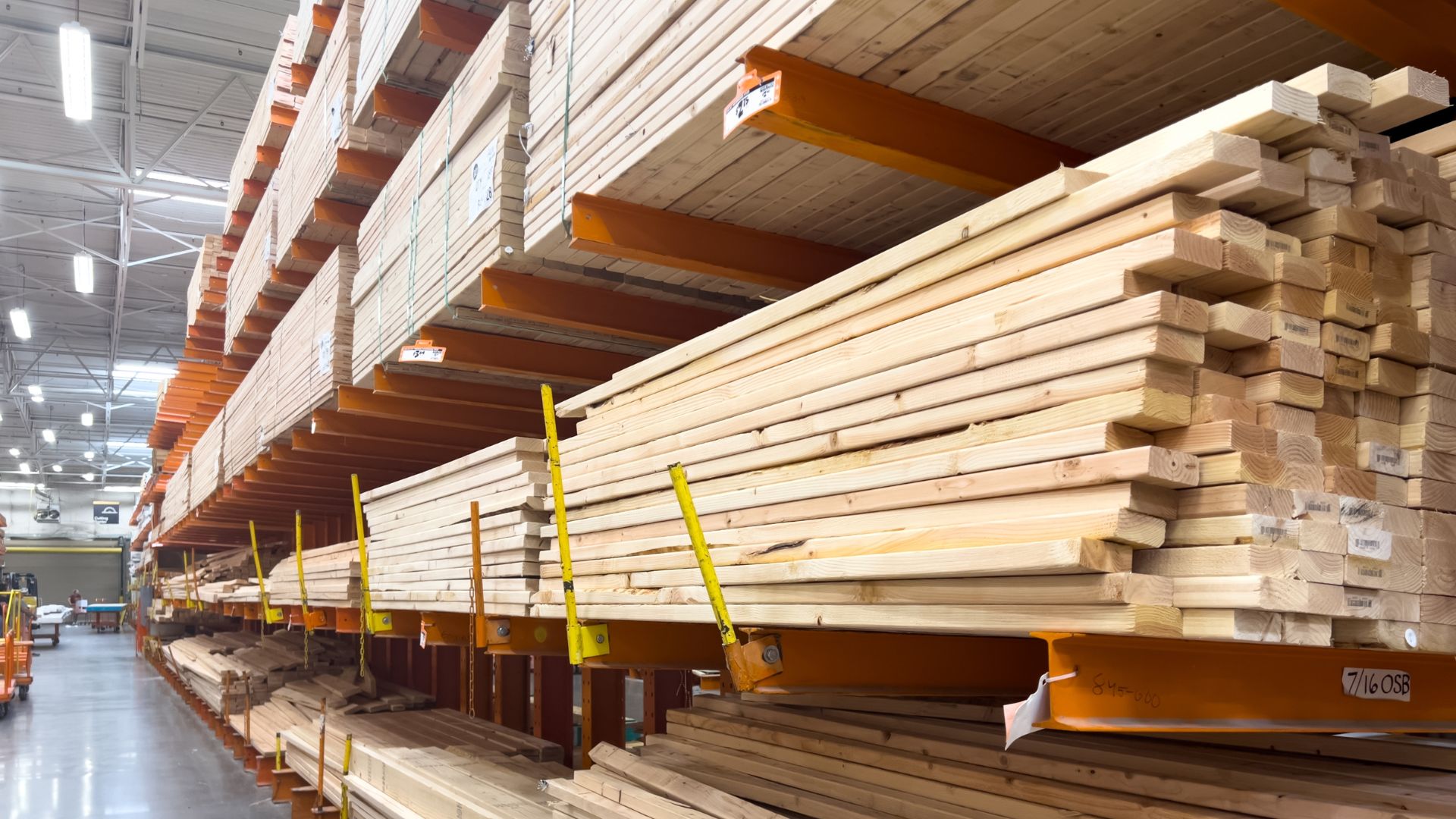 Neatly stacked lumber on orange shelves in a home improvement store.