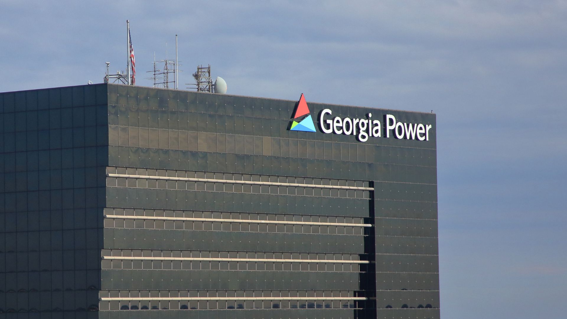 Exterior of the Georgia Power corporate headquarters building, showing the company logo and name atop a dark glass high-rise against a cloudy sky.