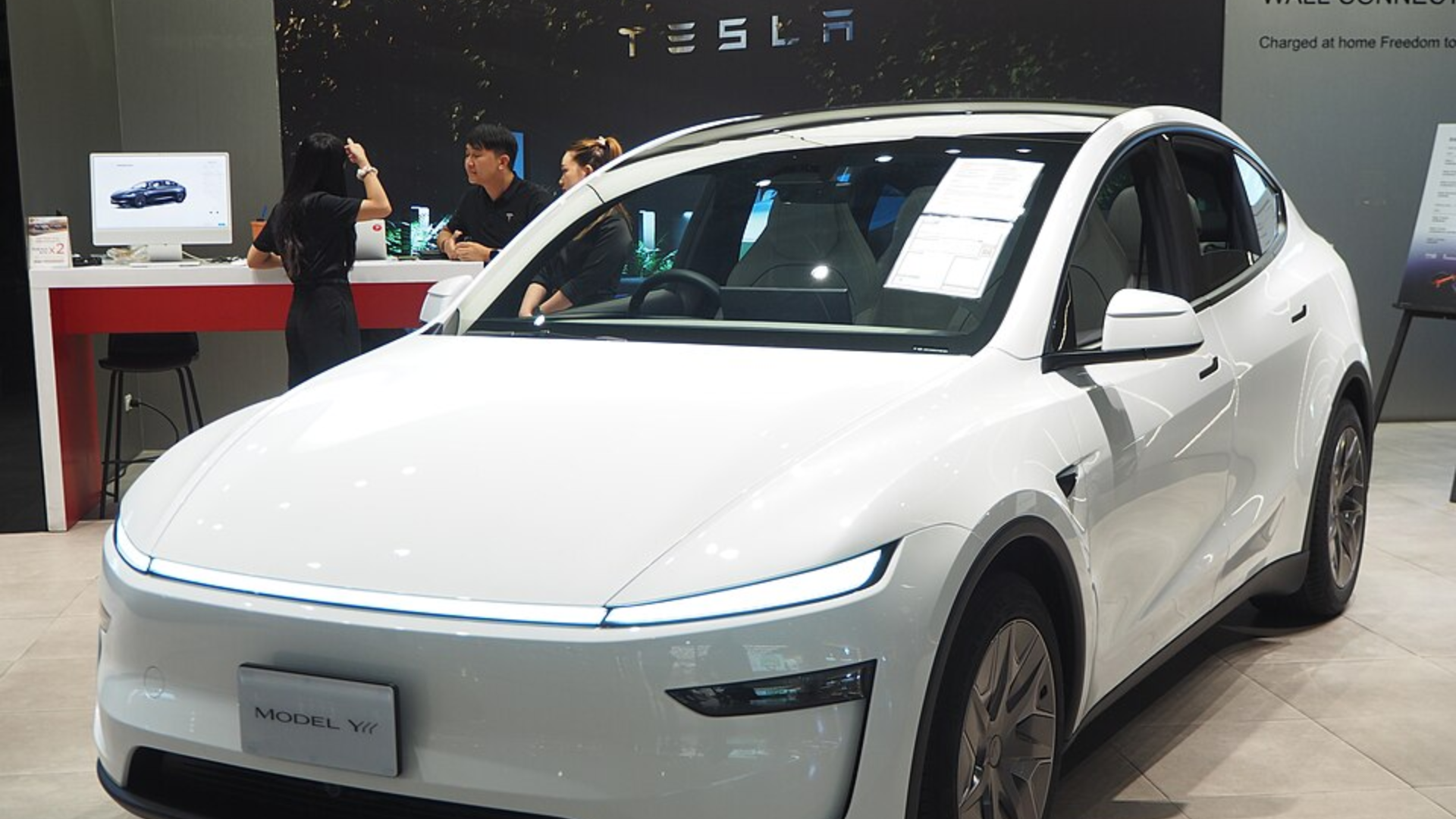 A white Tesla Model Y vehicle displayed in an auto showroom.