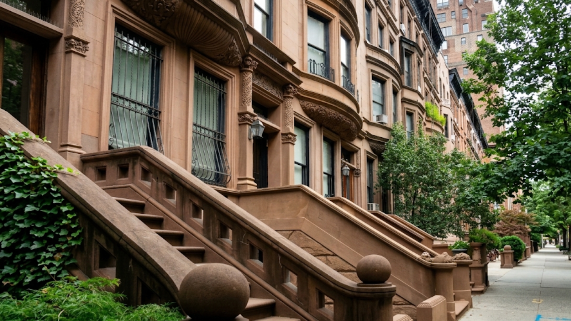 Manhattan Brownstone row houses with ornate stairs on the street, where median rent has climbed to $4,200 a month.