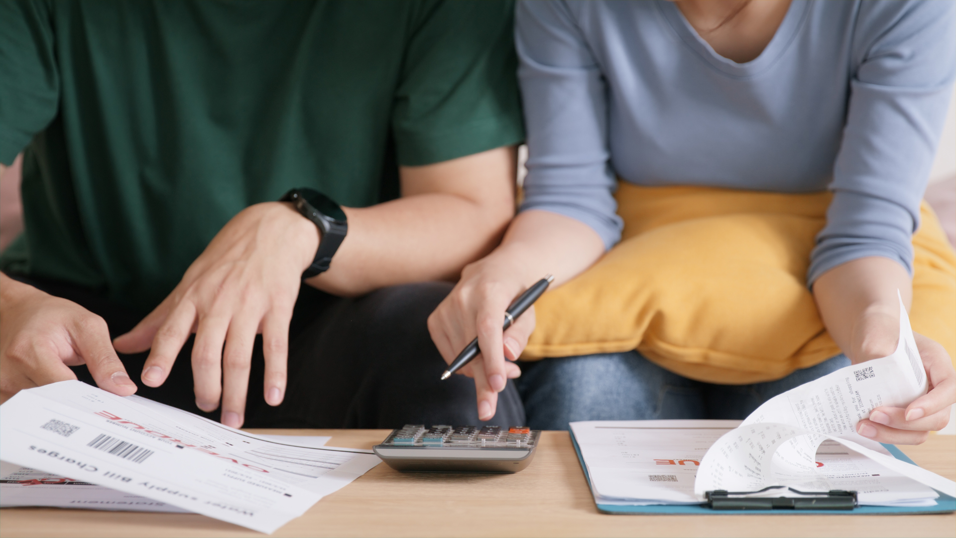 Couple using a calculator to review receipts and financial statements.