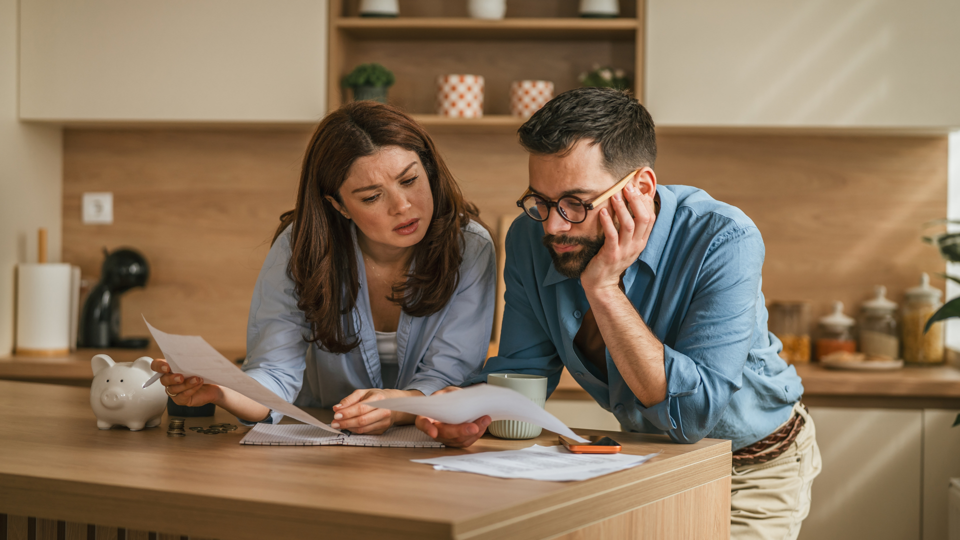 Concerned couple reviewing bills together at a kitchen island.