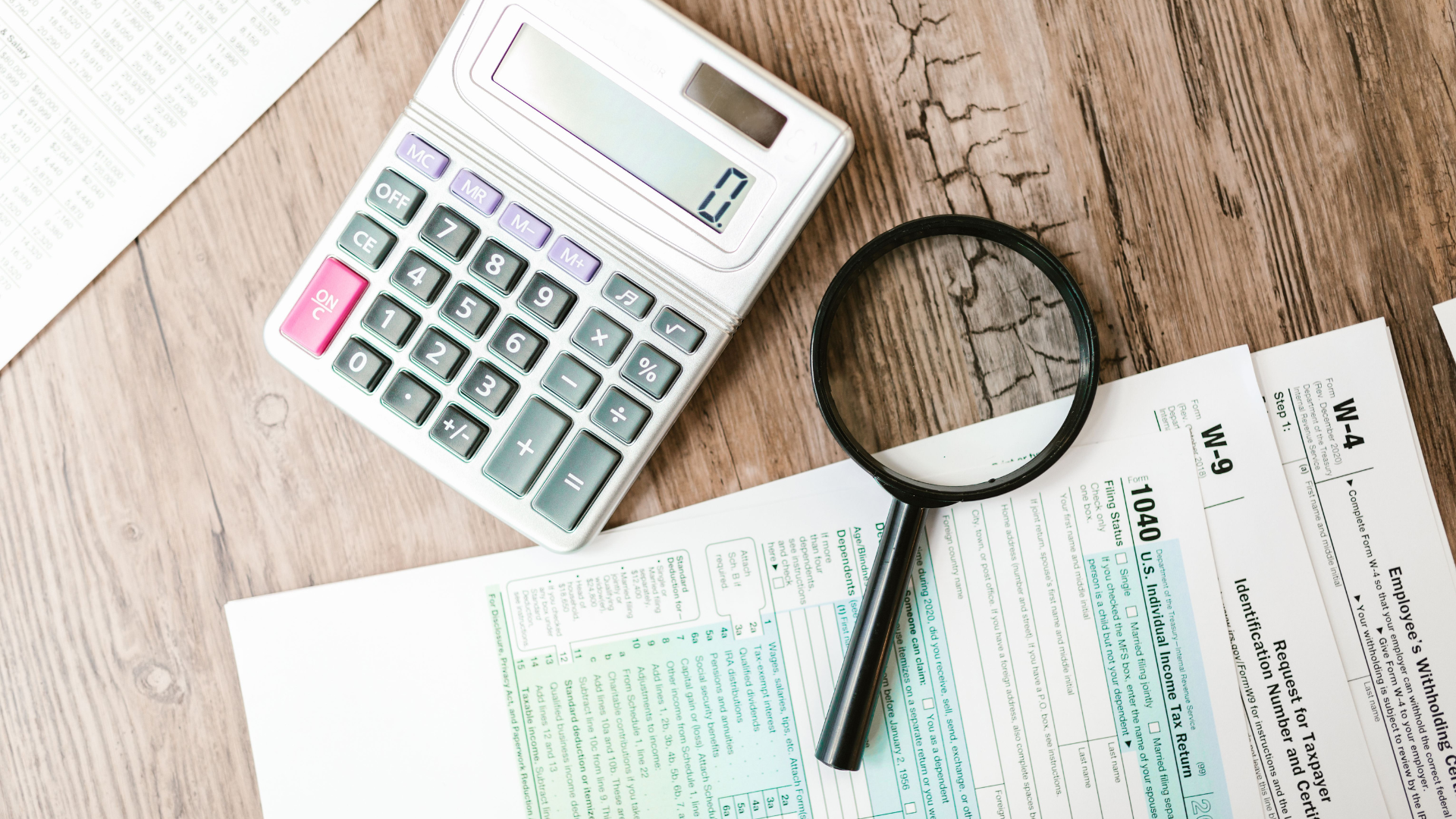 A magnifying glass hovers over financial paperwork, perfect for finance themes.