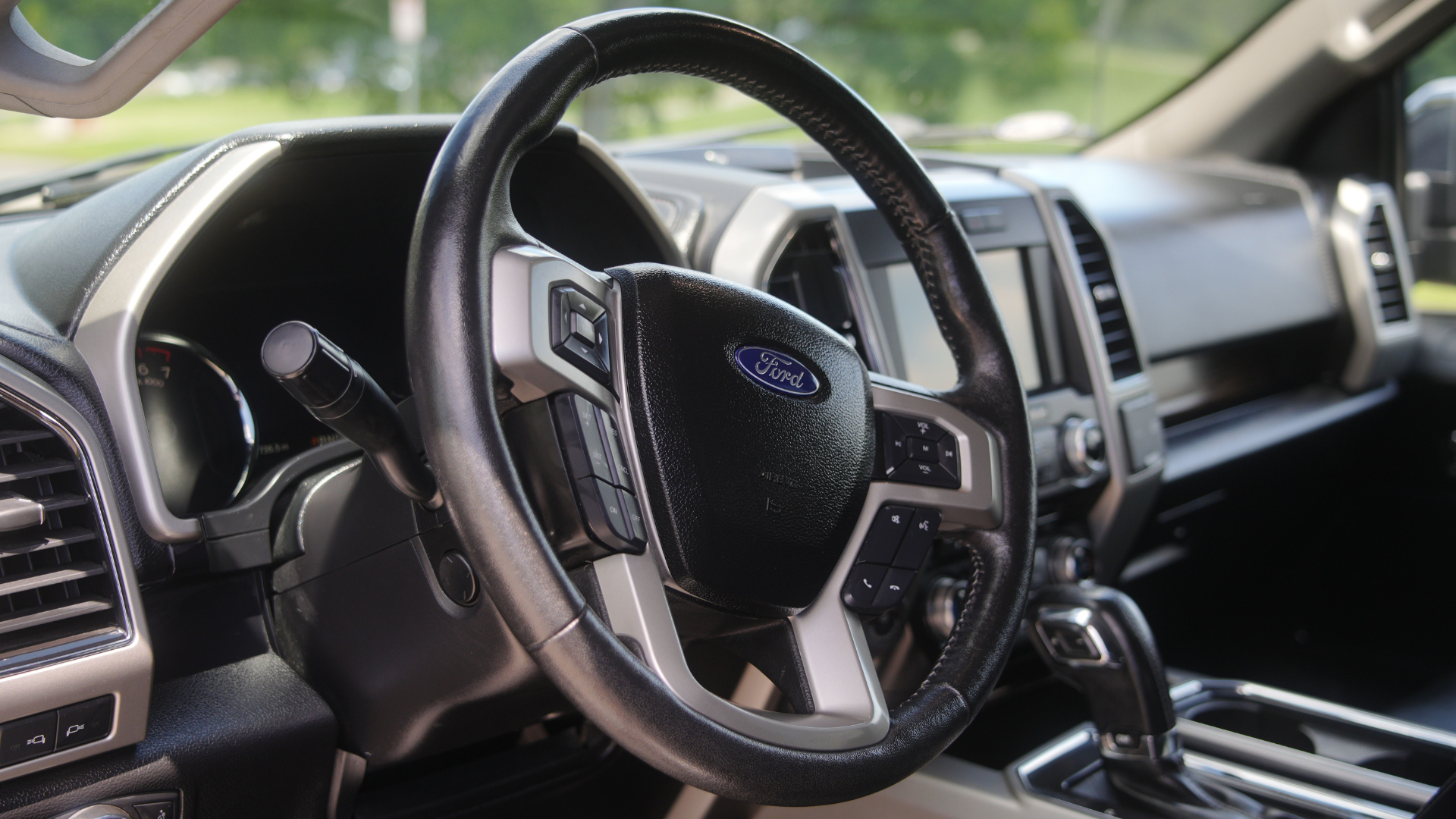 An interior view highlighting the leather-wrapped steering wheel and dashboard of a modern Ford truck.