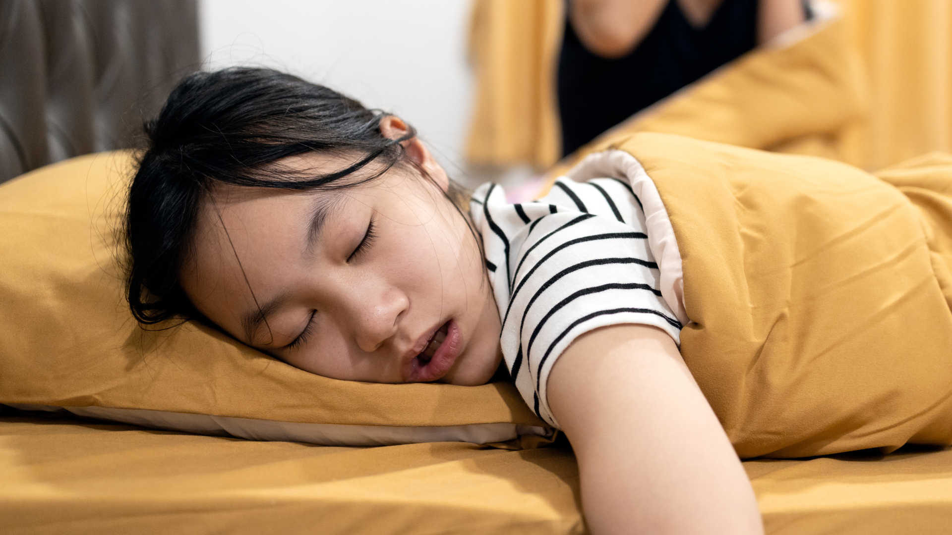  A girl sleeps mouth-breathing on a bed.