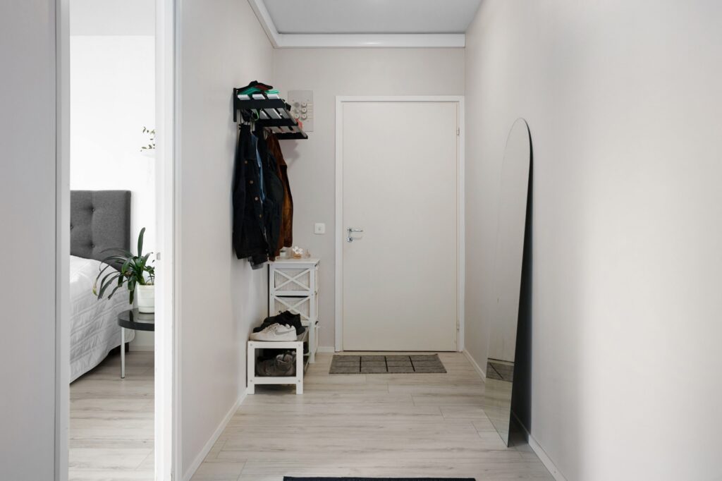 Clean, organized home entryway with shoes on a rack, coats hanging by the door and an uncluttered floor.
